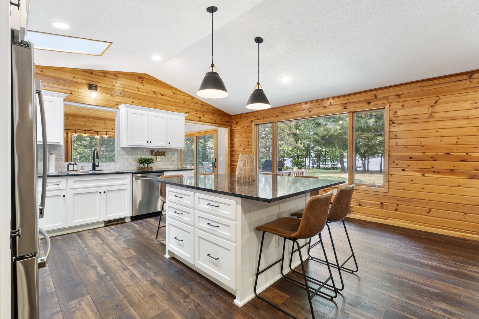 Bright and spacious kitchen with warm pine walls, granite counters, and skylights overlooking peaceful wooded grounds. The perfect retreat for morning coffee and home-cooked meals.