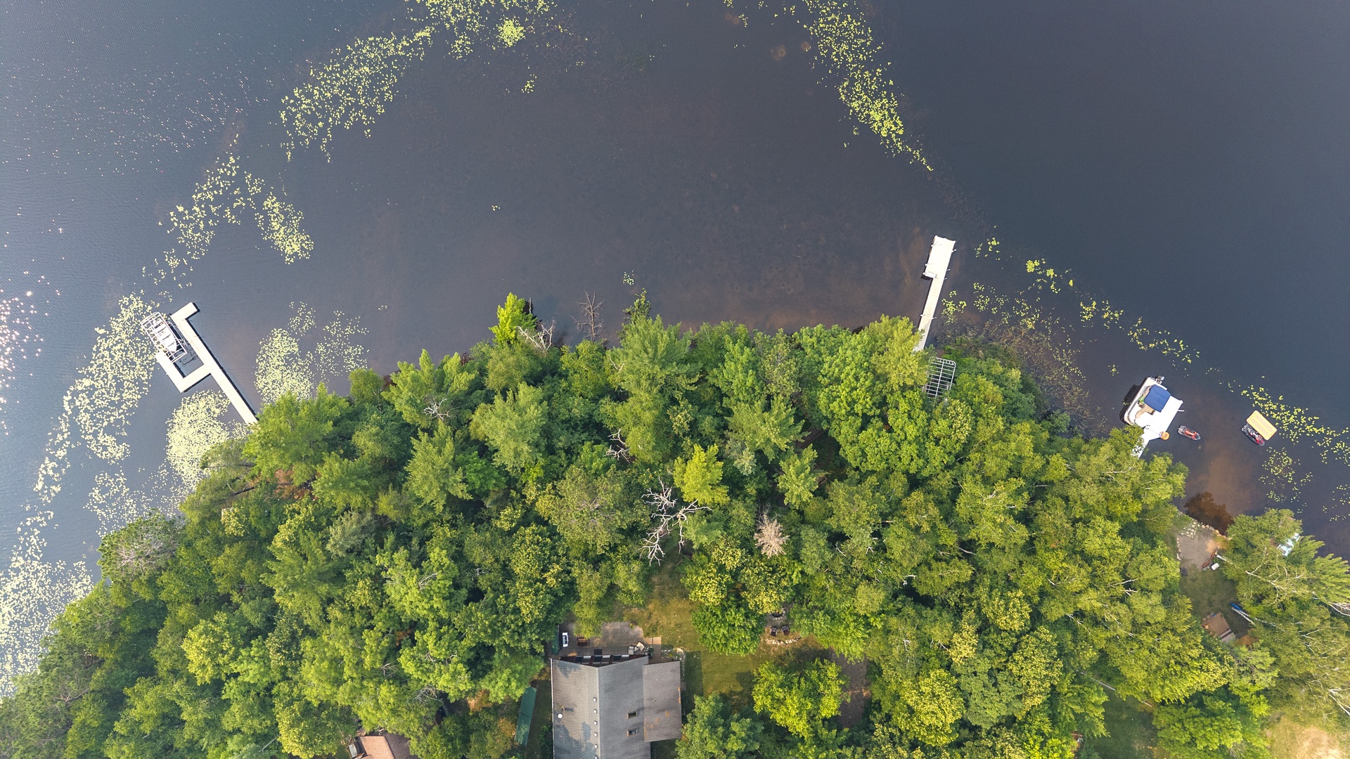 Aerial view capturing the property's secluded location on a private, tree-covered island surrounded by calm lake waters, with boat access and natural shoreline defining the retreat.