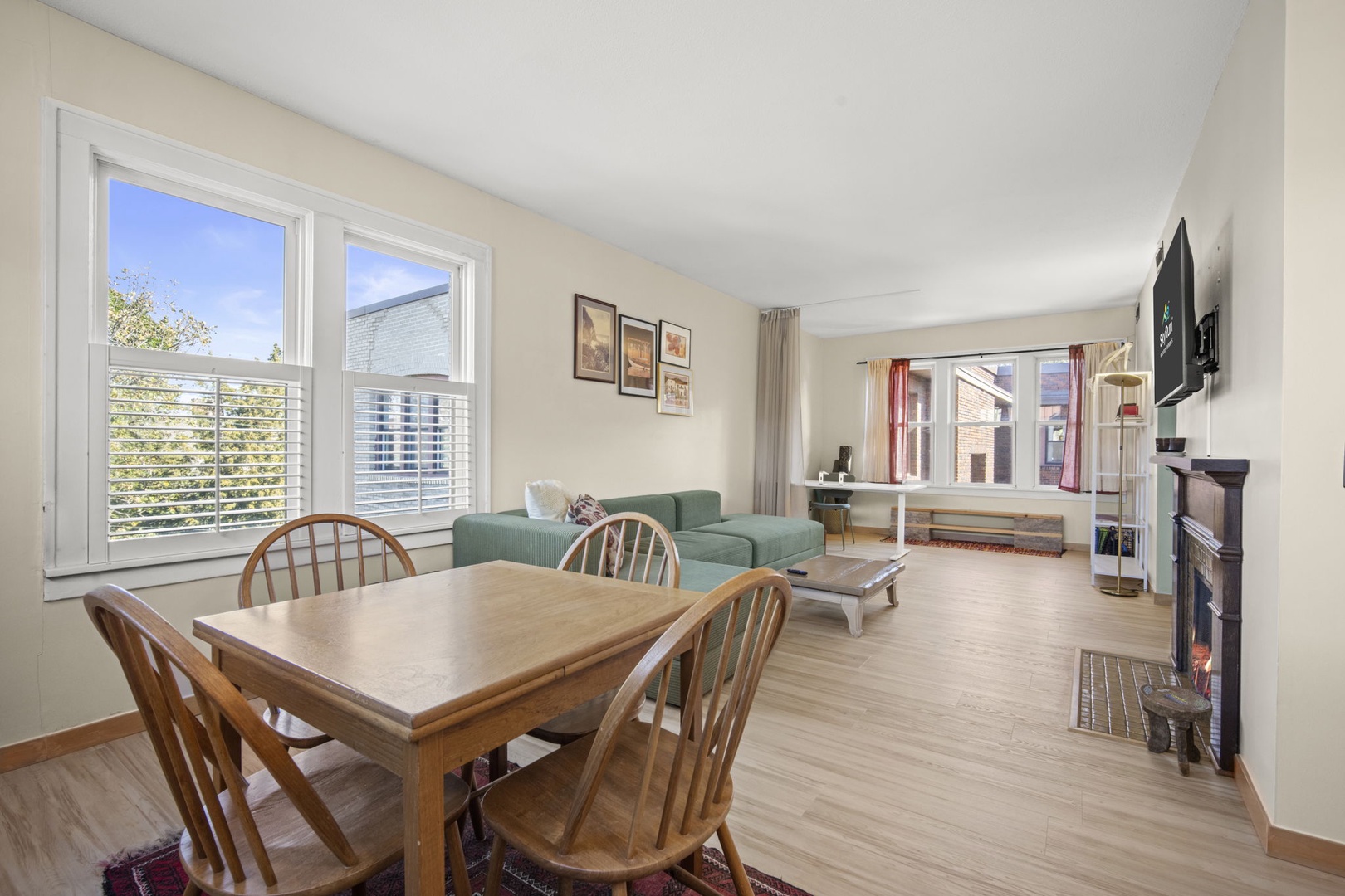 Step into your sunlit open-concept living space, where a cozy dining table and plush seating invite you to unwind after exploring the neighborhood.