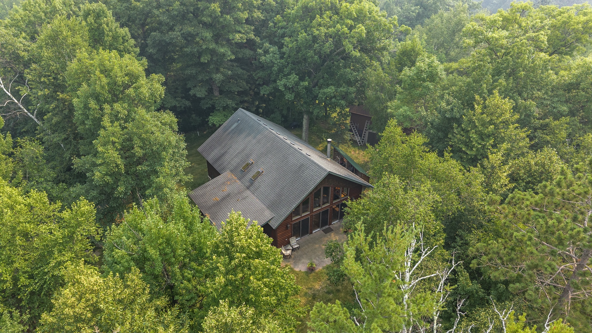 Aerial view of a secluded cabin nestled in lush forest, offering privacy and natural surroundings.