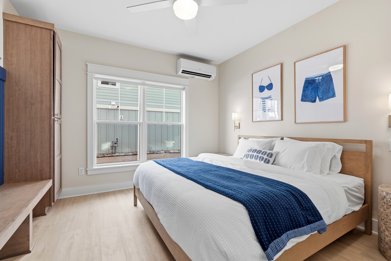 Coastal king bedroom with ceiling fan AC and beach themed art