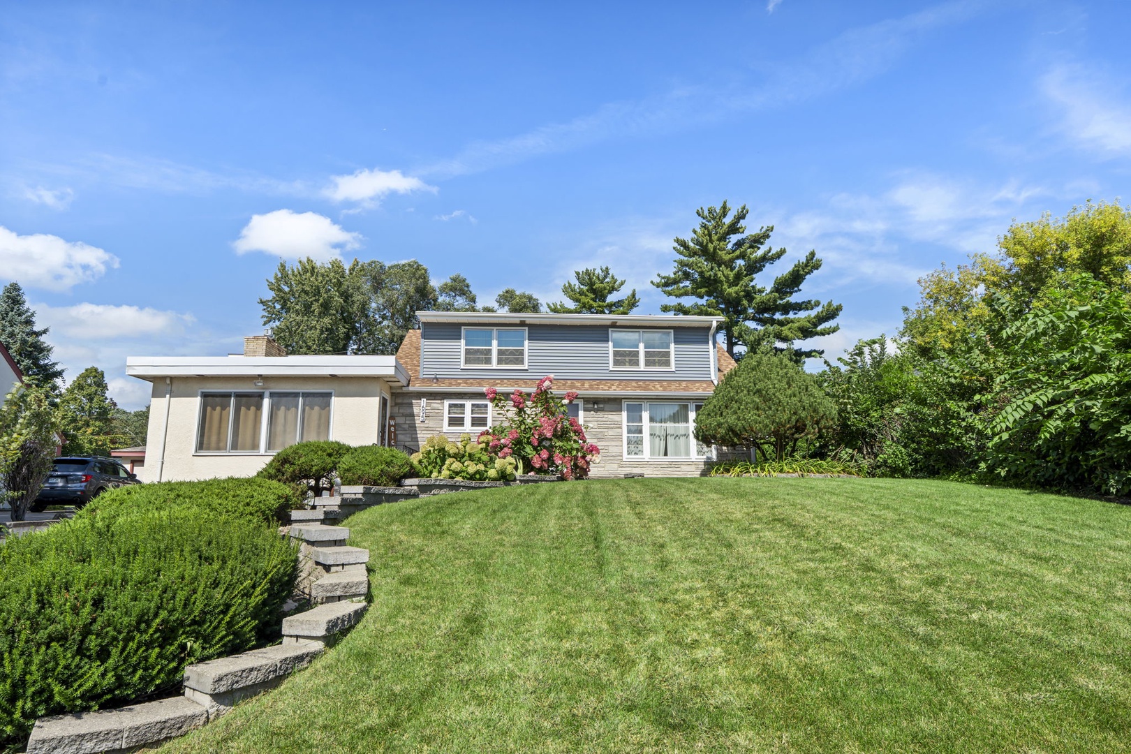 Modern two-story home nestled on landscaped grounds with mature trees and manicured lawn providing a peaceful suburban setting.