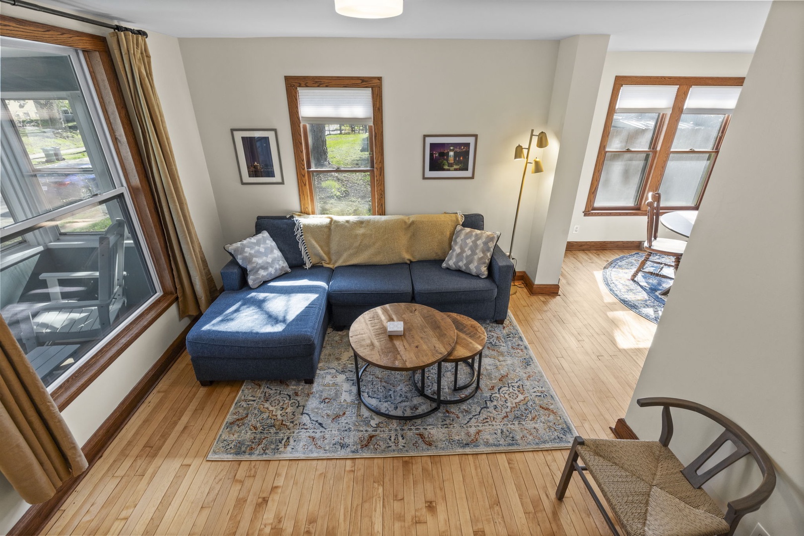 Bird's-eye view of the living room shows the full open floor plan — sectional sofa, nesting coffee tables, and warm natural light from multiple windows.