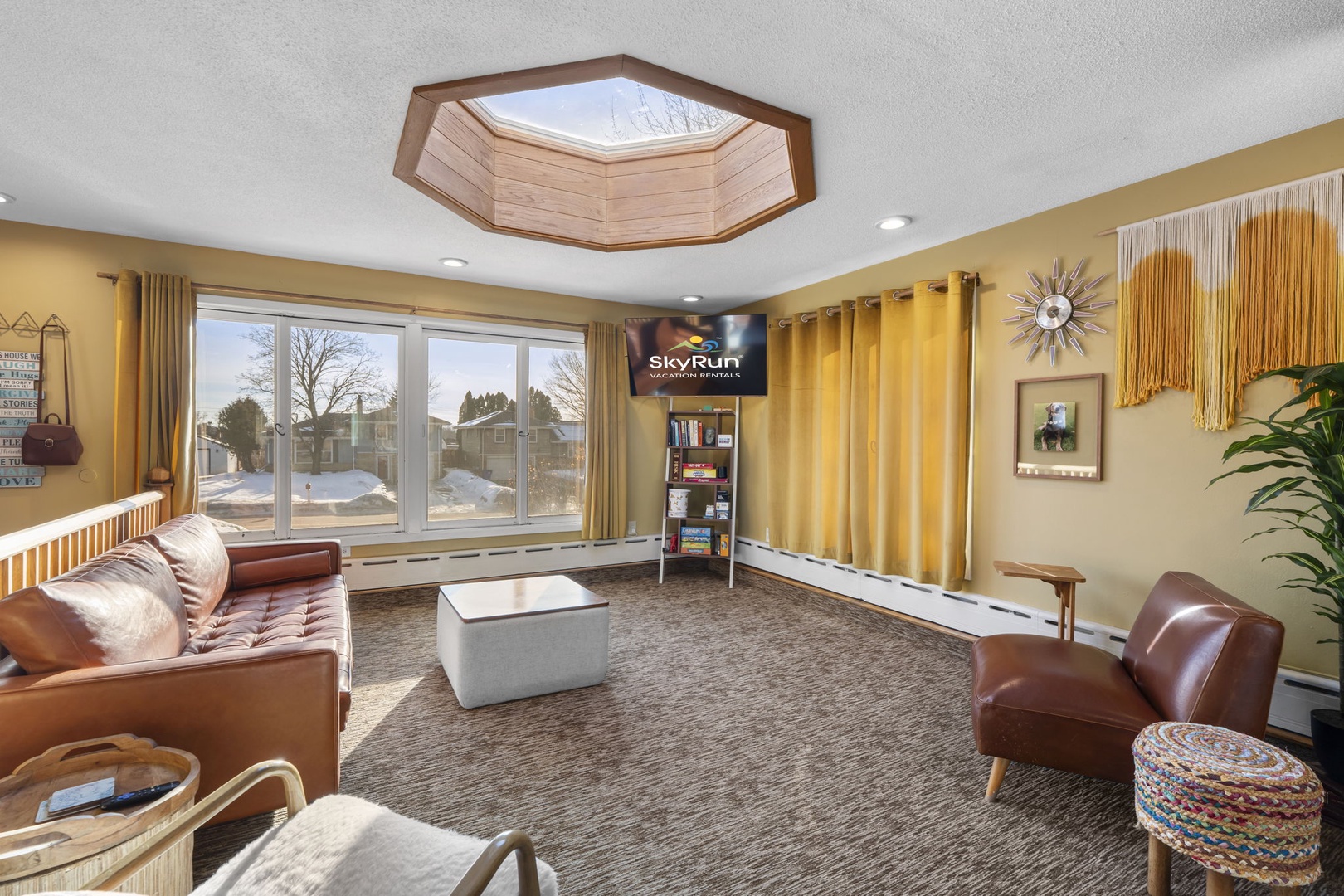 Unwind in this bright communal lounge with leather seating, warm tones, and natural light streaming through expansive windows.