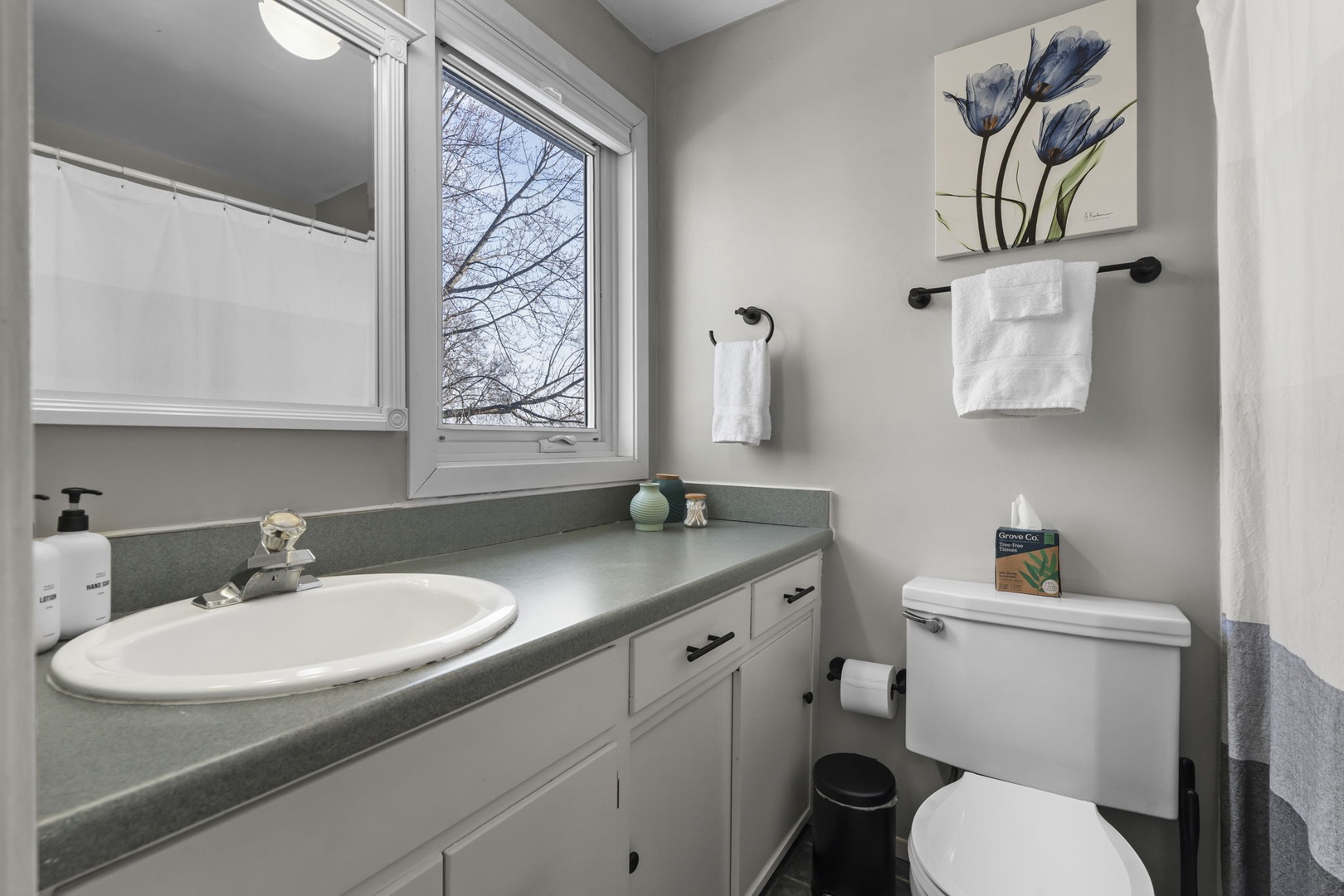 Your private bathroom features fresh towels, thoughtful amenities, and natural light from the window for your comfortable stay.