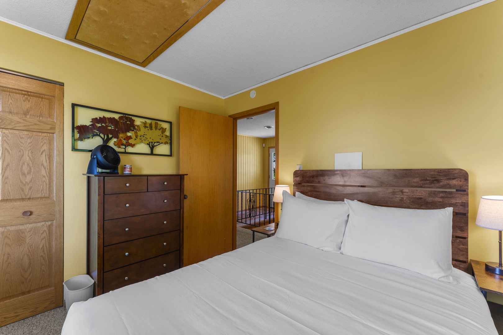 Sink into crisp, white linens on your cozy bed in this cheerful, sunlit room. The warm yellow walls and rustic wood headboard create a welcoming retreat after your day of adventure.