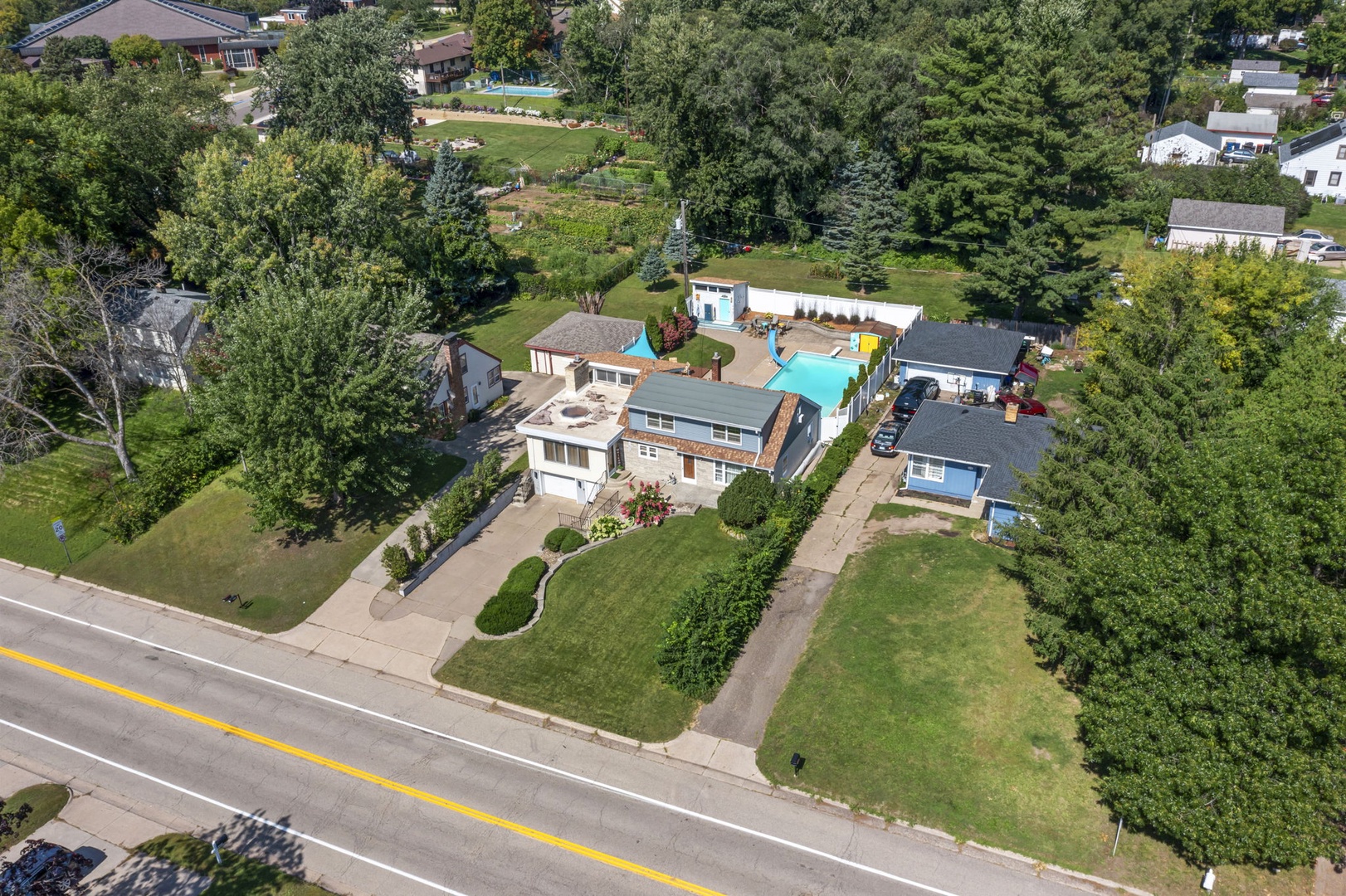 Aerial view showcasing the property nestled in a tree-lined residential neighborhood with spacious grounds and peaceful surroundings.