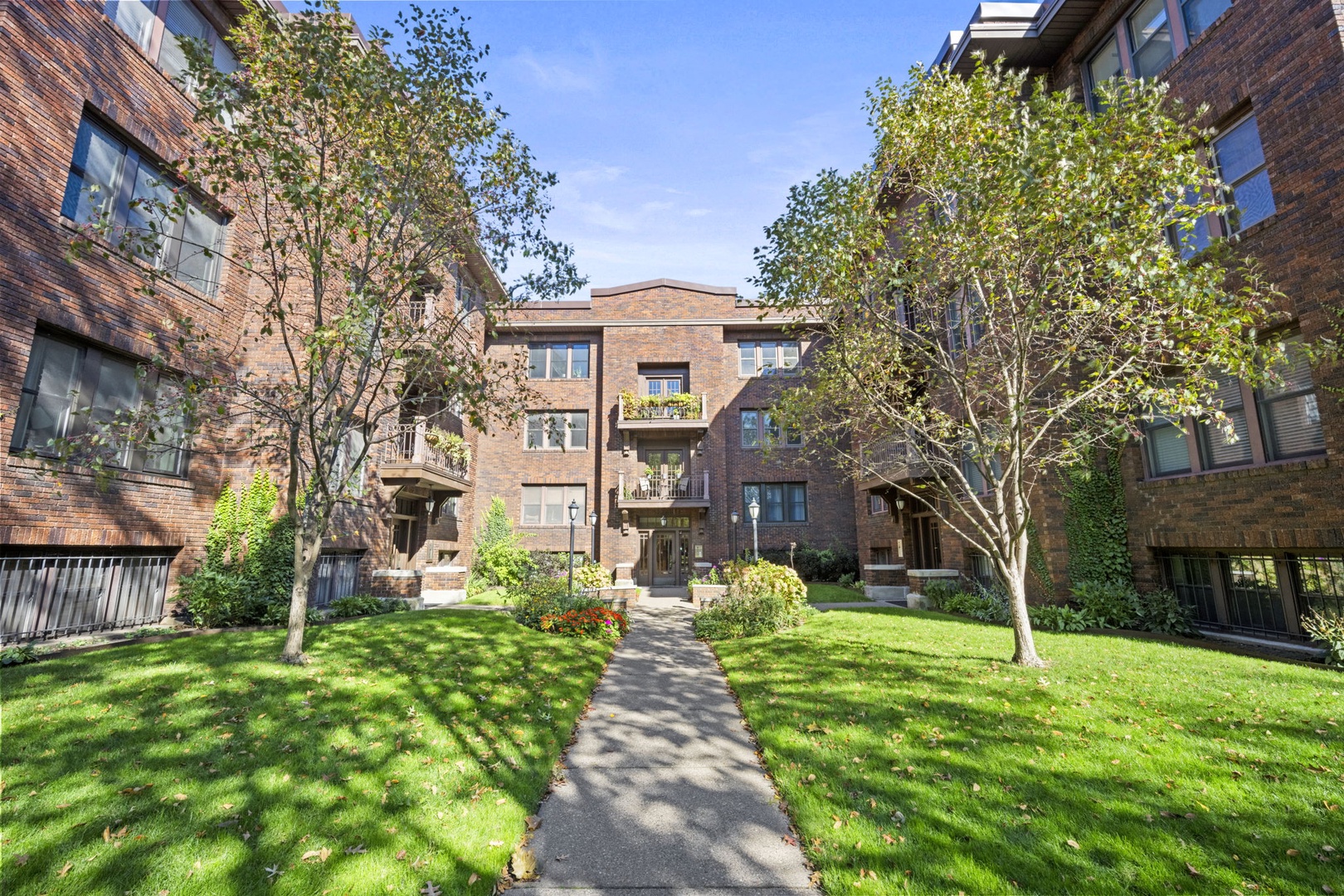 A welcoming multi-story brick building surrounded by mature trees and lush green lawns, offering a quiet residential setting for your arrival and stay.