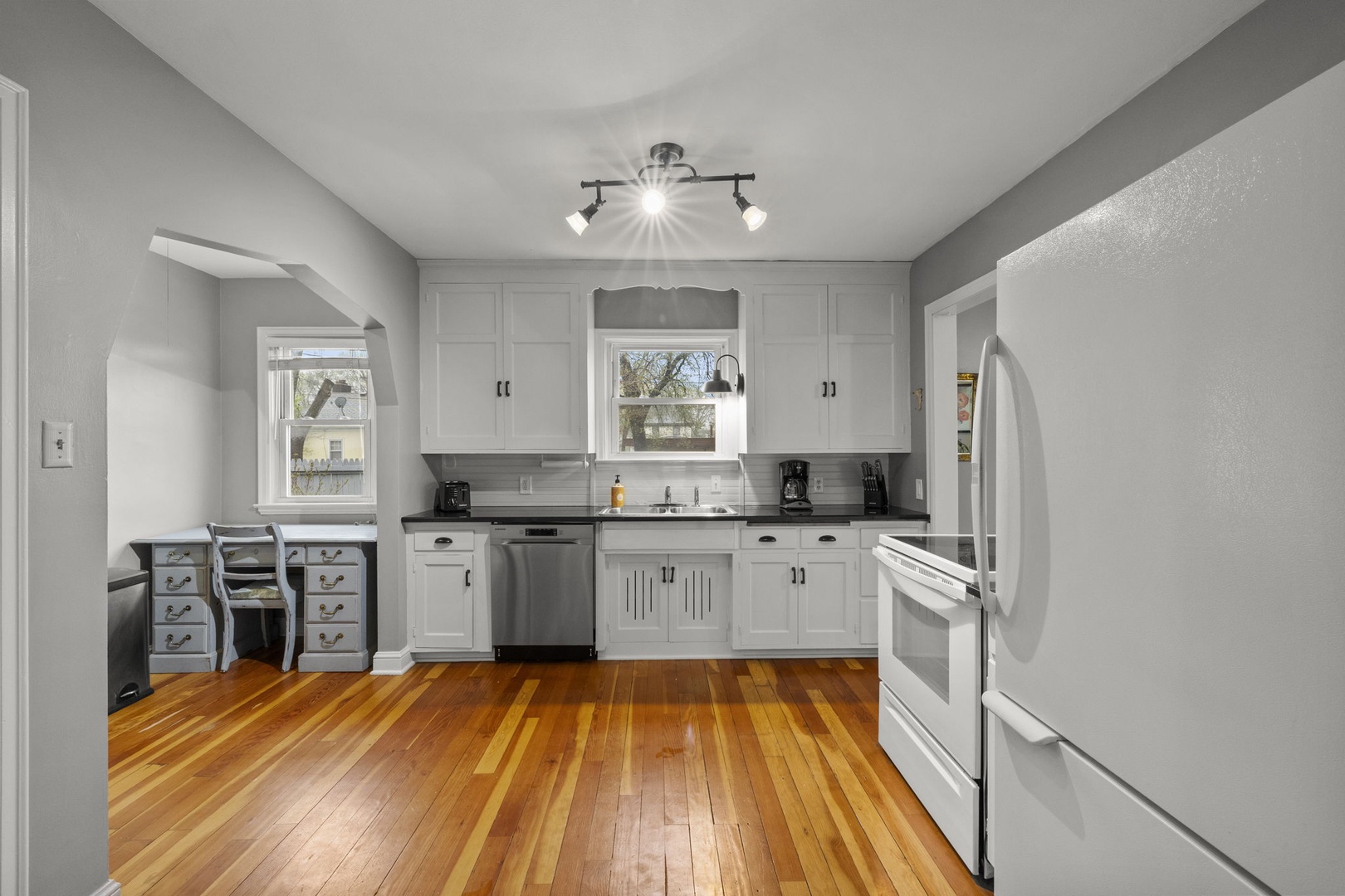 This bright, fully-equipped kitchen invites you to prepare your favorite meals with modern appliances, ample cabinetry, and warm hardwood floors that make the space feel both functional and welcoming.