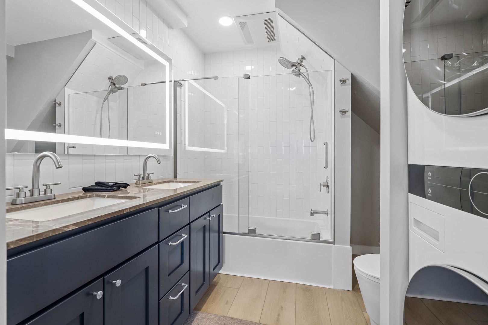 Step into your spa-like bathroom with dual vanities, sleek fixtures, and a luxurious glass-enclosed tub-shower combo.