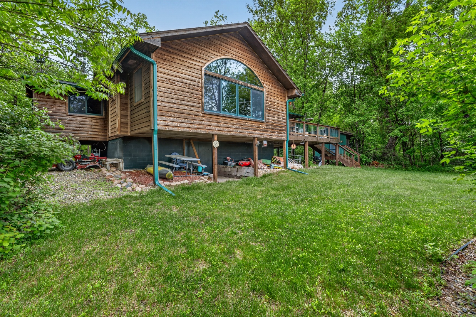 This charming cedar-sided retreat sits nestled among mature trees, offering a private, nature-surrounded escape with spacious decks and a welcoming lower-level patio.