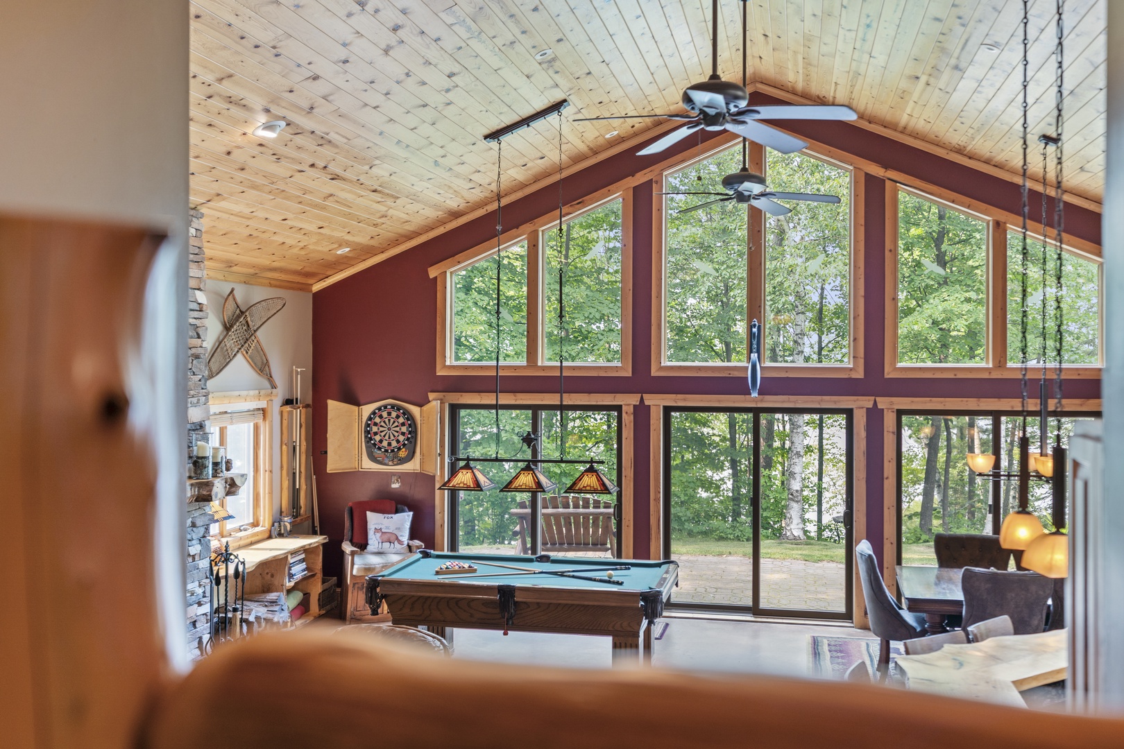 Step into your private game room, where soaring wood-beamed ceilings and floor-to-ceiling windows frame lush forest views. Challenge friends to billiards under Tiffany-style lighting, then unwind in plush armchairs as natural light floods the space.