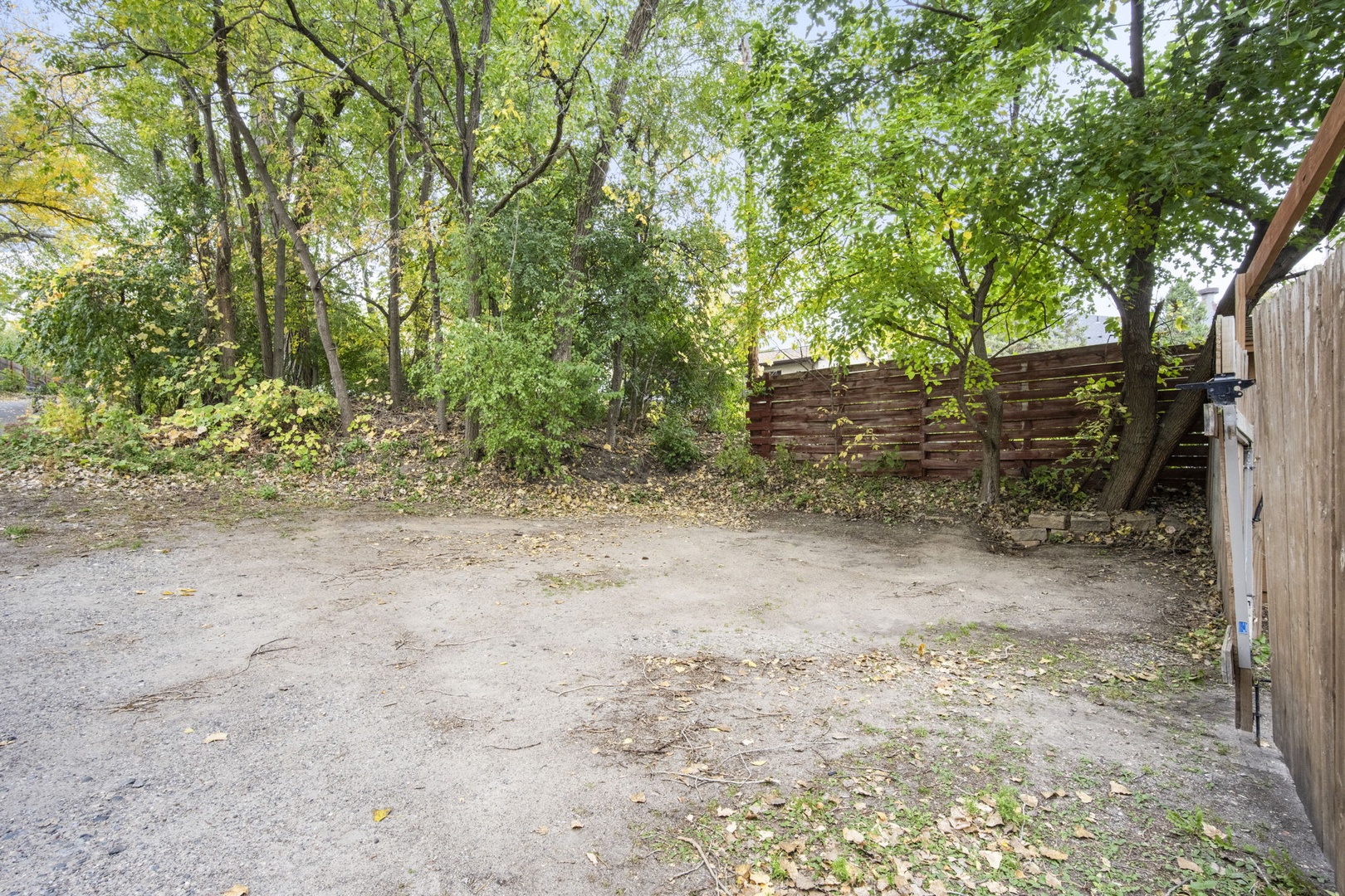 Private parking area bordered by mature trees and a wooden fence, providing secure space for your vehicle during your stay.