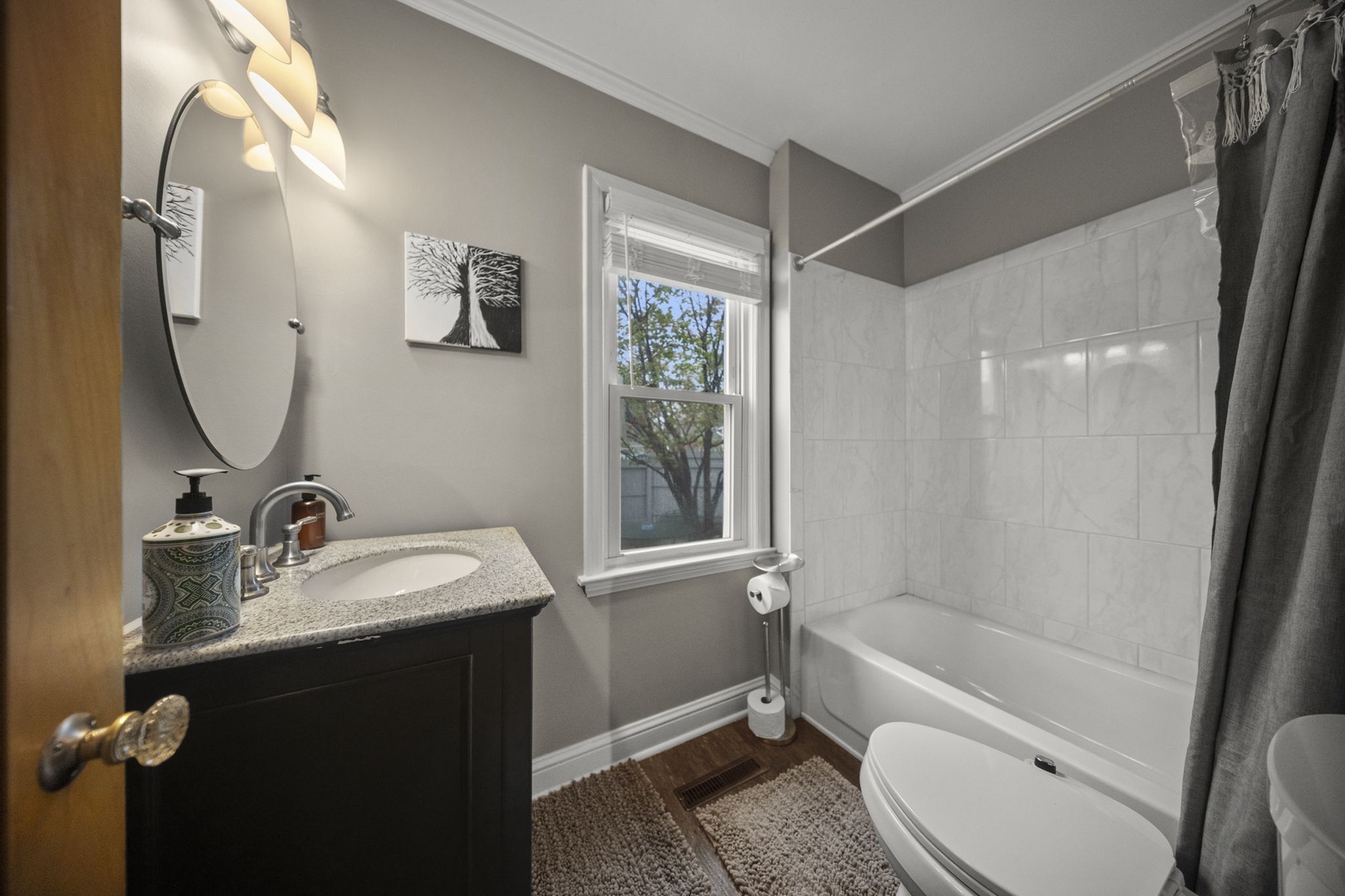 Your private bathroom features a fresh, modern design with a full tub-shower combo, stylish vanity, and soft natural light streaming through the window.