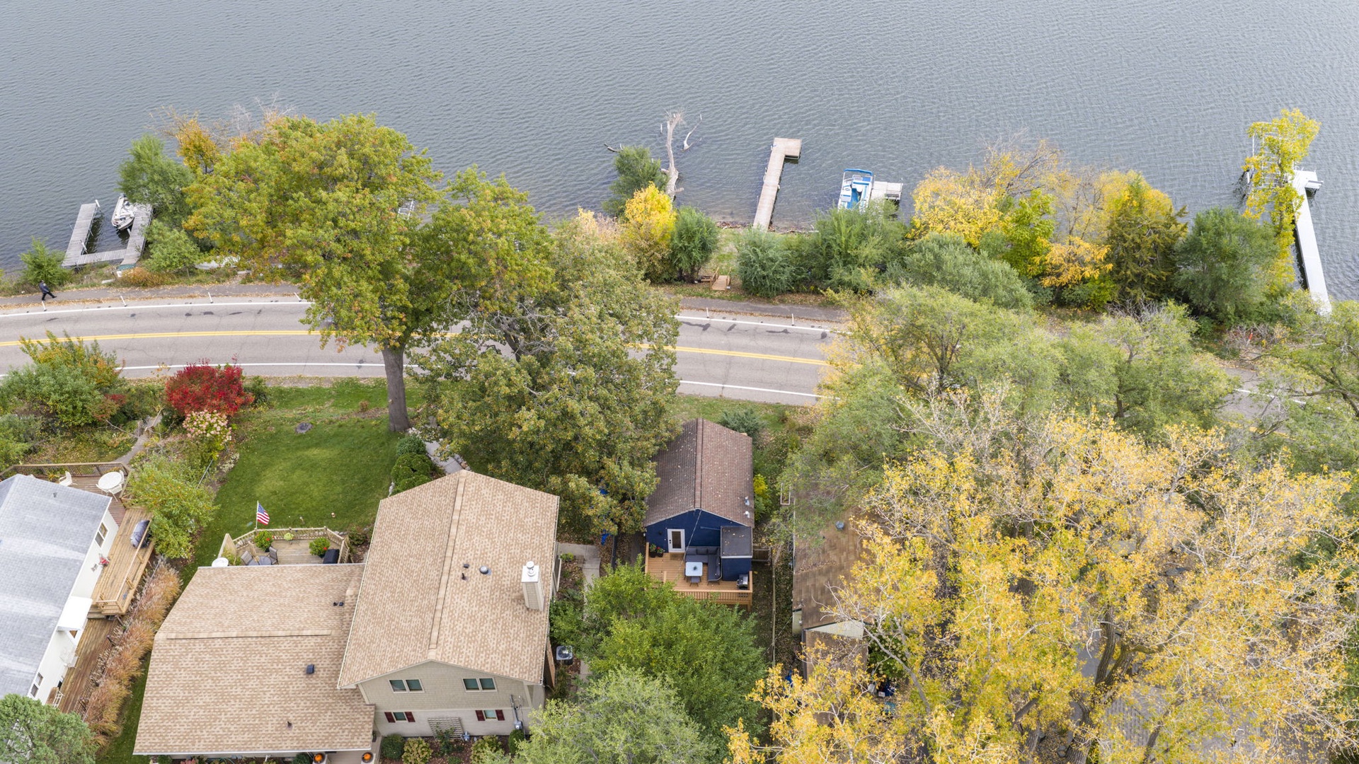 Aerial view of the home nestled among autumn trees, with a lake visible in the surrounding area.