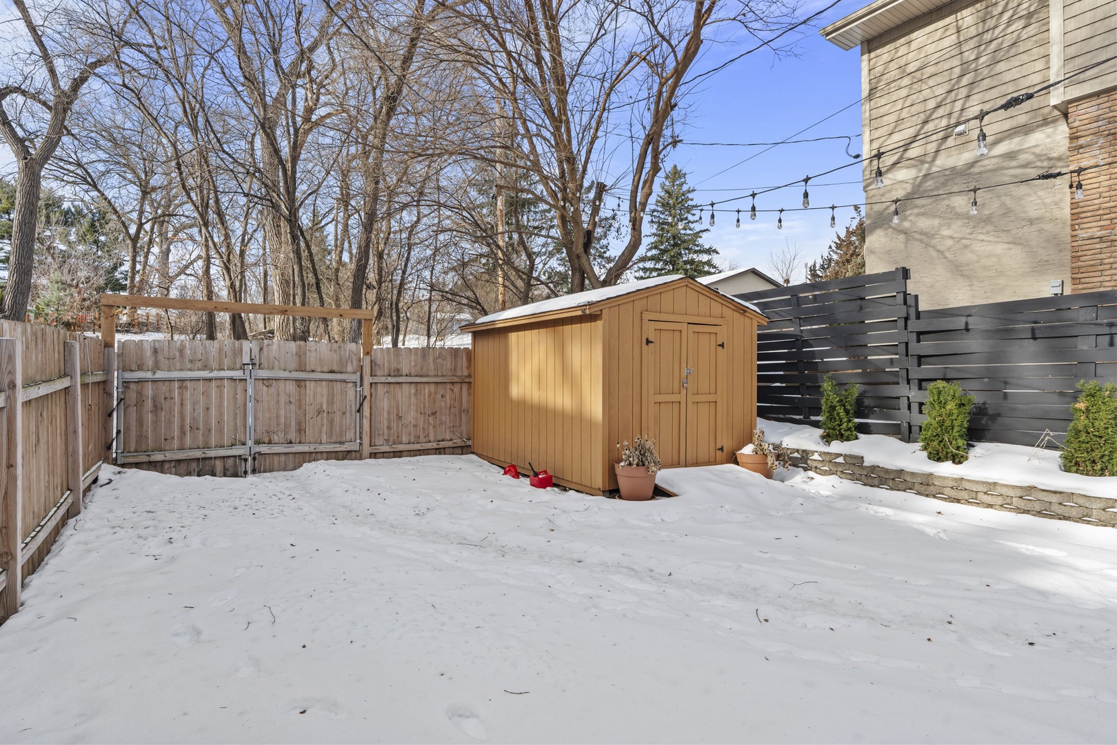 Snow-covered backyard with wooden shed and modern fencing creates a peaceful winter retreat setting.