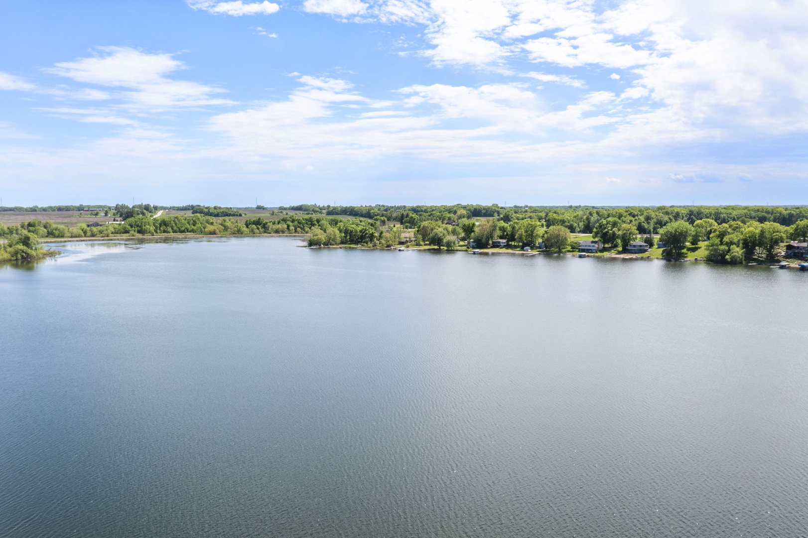 Aerial view of a tranquil lake surrounded by lush greenery and shoreline properties, offering a peaceful natural setting for the vacation rental.