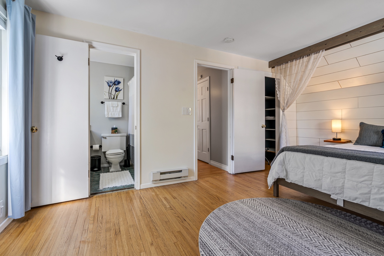 Your spacious bedroom features warm wood floors, cozy linens, and a convenient ensuite bathroom for ultimate comfort and privacy.