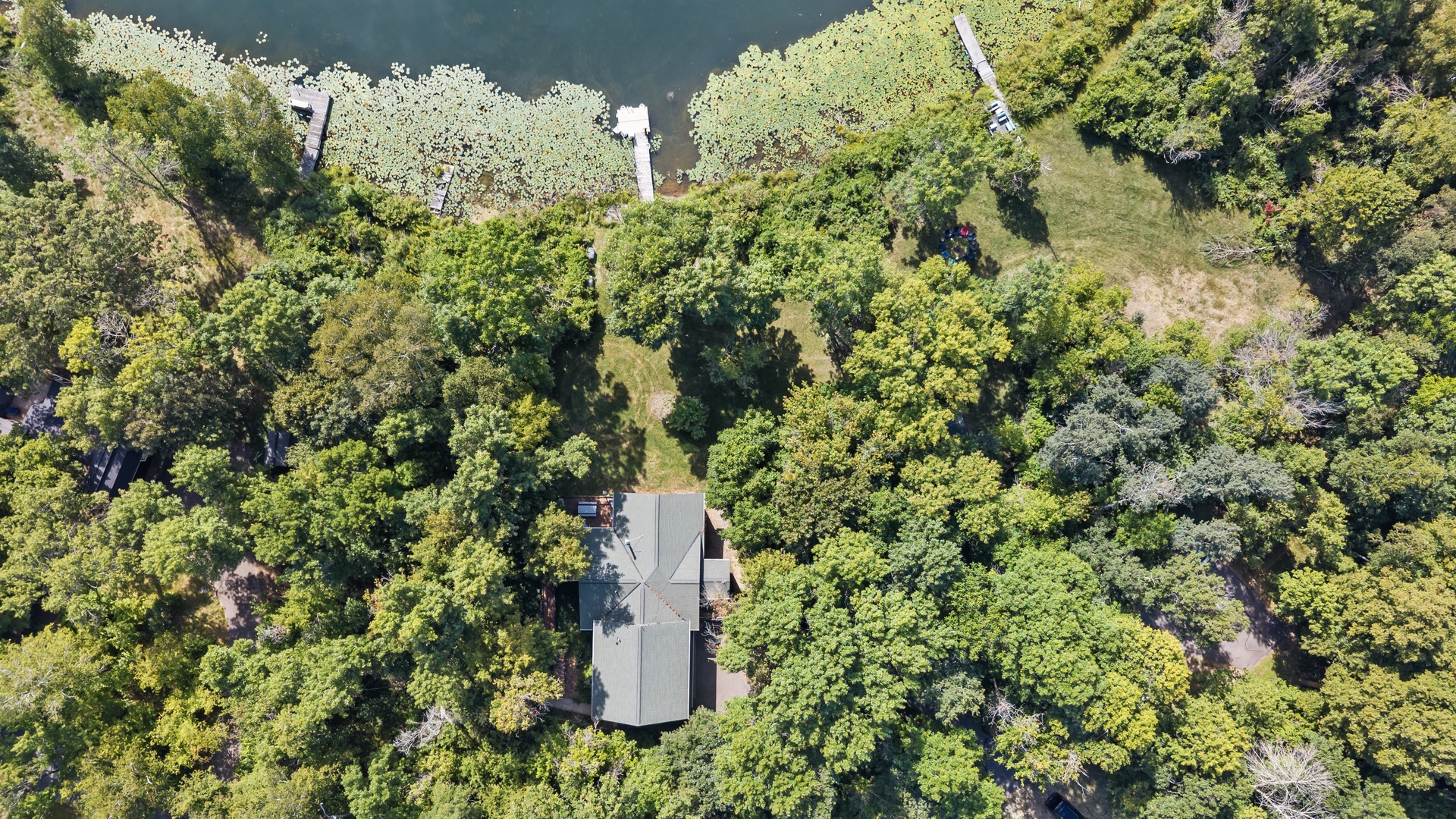 An aerial view reveals the property nestled amid lush greenery, with private water access and a peaceful wooded setting.