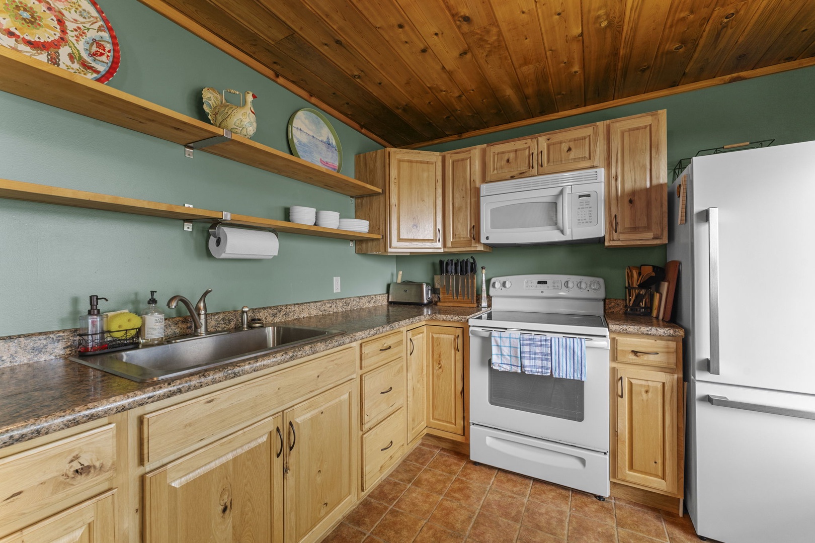 Cook your favorite meals in this fully-equipped kitchen featuring warm wood cabinetry, granite countertops, and all the modern appliances you need to feel right at home.