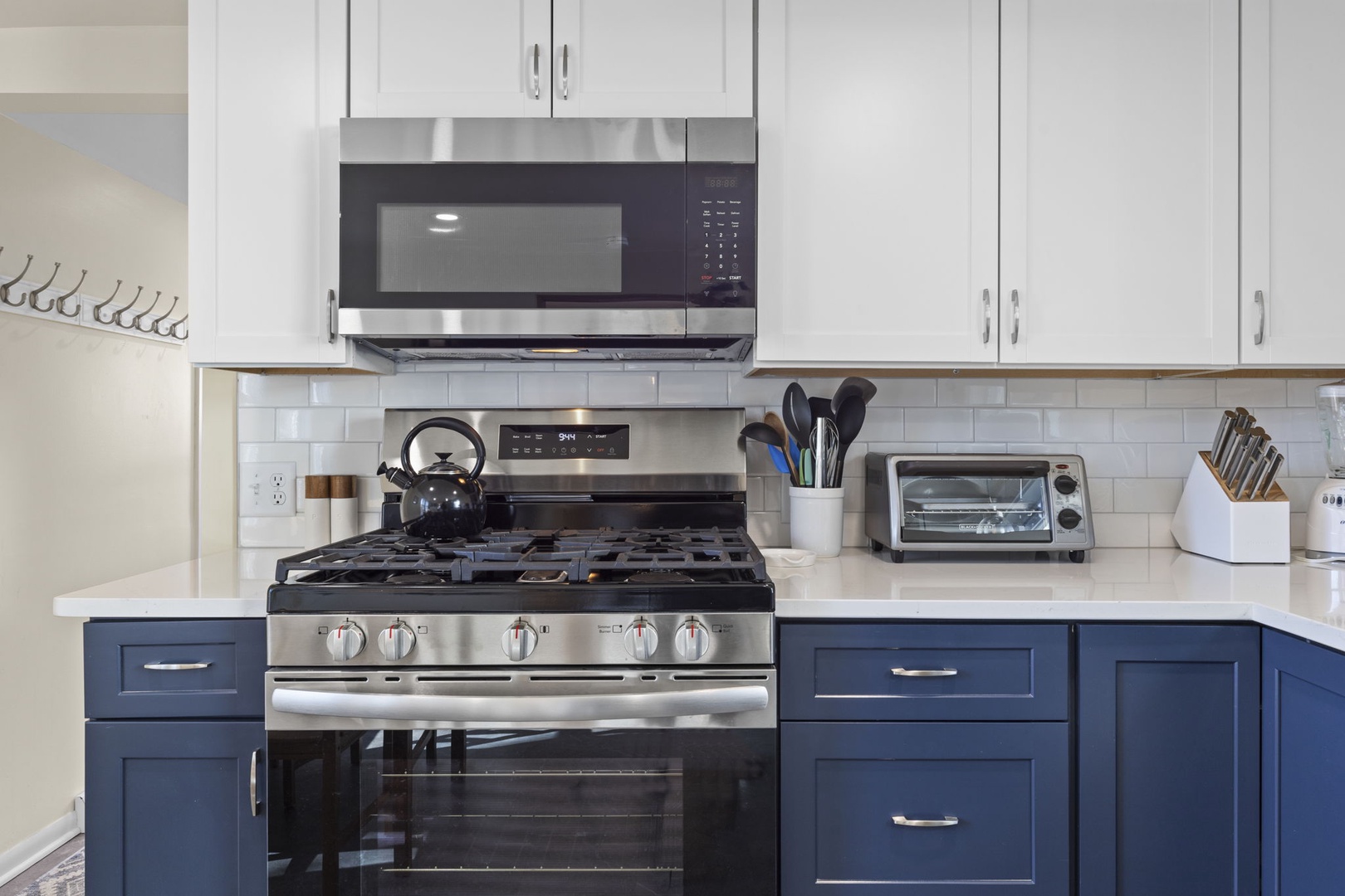 Gas range with five burners, over-the-range stainless microwave, and toaster oven — everything a home chef needs in a beautifully updated kitchen.