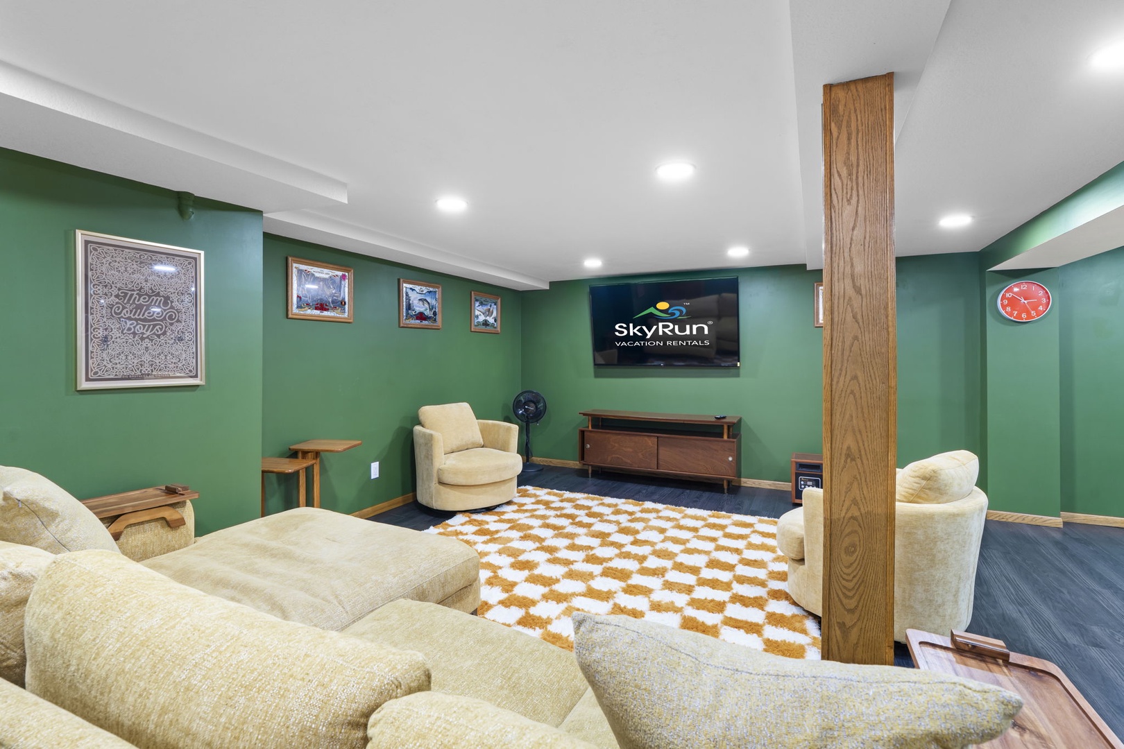 Unwind in your private basement lounge with plush seating, entertainment setup, and vibrant green walls creating the perfect retreat.