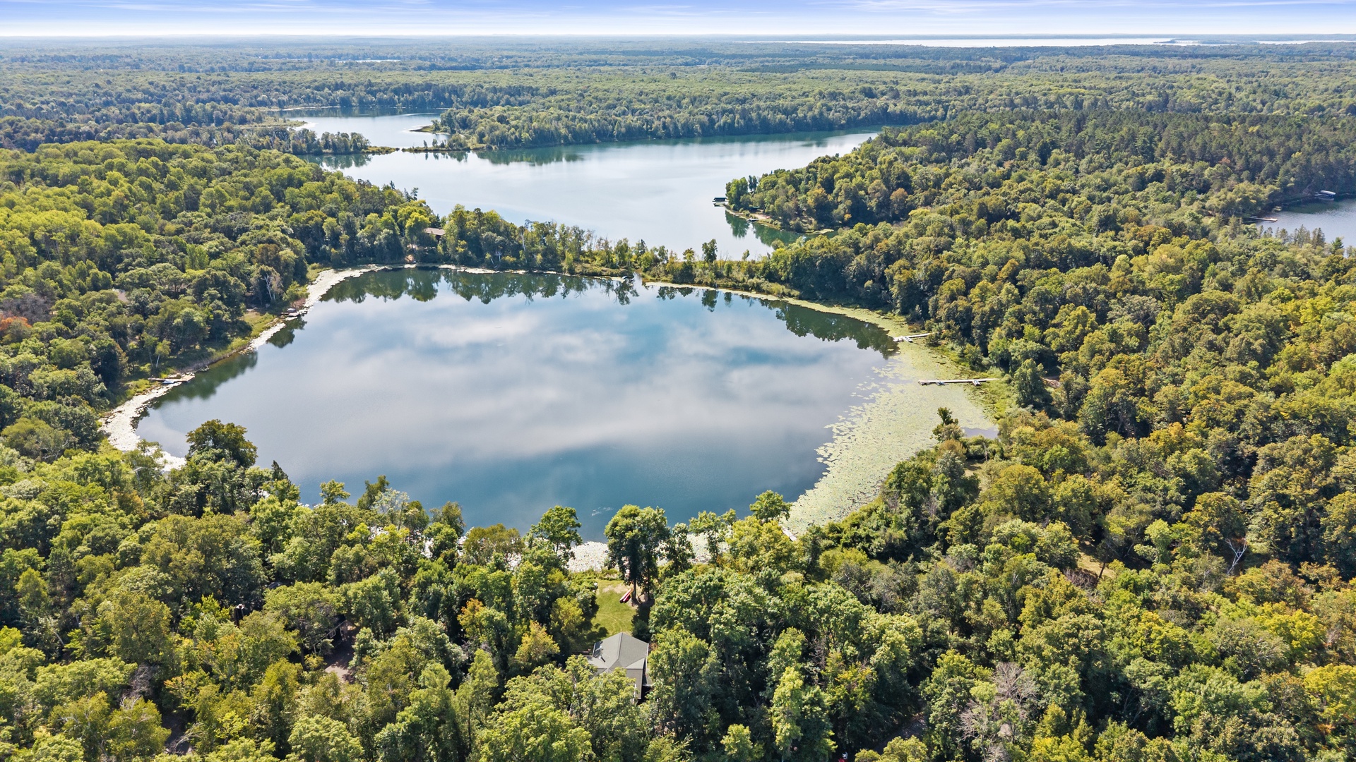 Aerial view of the property's pristine lakefront setting, surrounded by lush forests and tranquil waters perfect for a peaceful retreat.