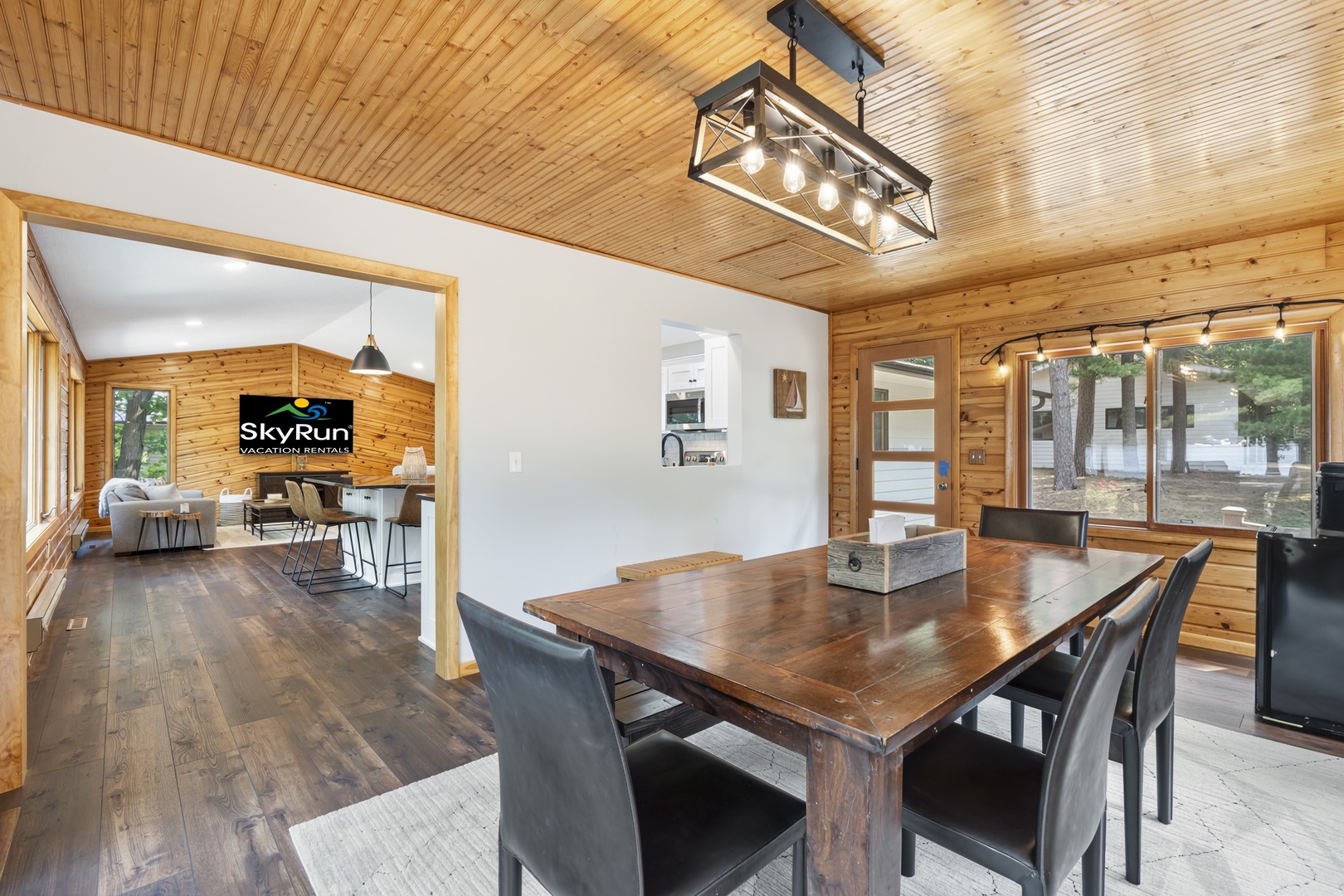 Gather around the rustic dining table under warm wood ceilings, where natural light pours in through expansive windows. Your open-concept retreat flows seamlessly into cozy living spaces, blending modern comfort with cabin charm.