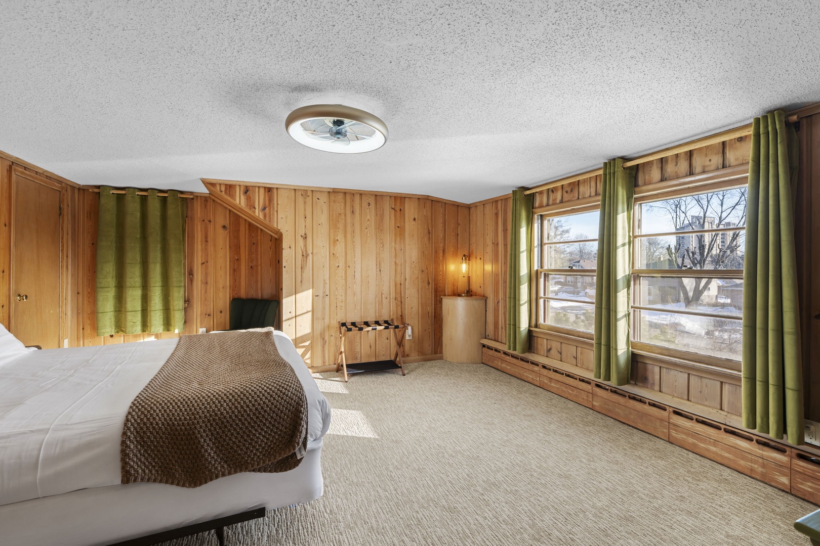 Relax in your spacious wooden bedroom with warm alpine charm and peaceful views through large windows.