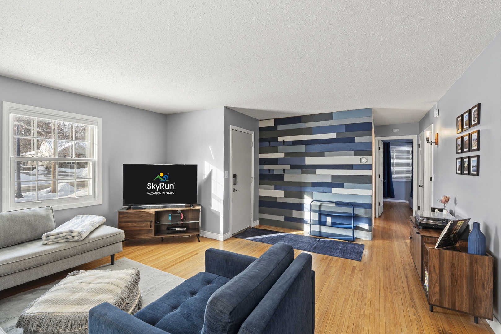 31 — Main Floor Open Concept Living Room with Smart TV Blue Plank Accent Wall and Entry