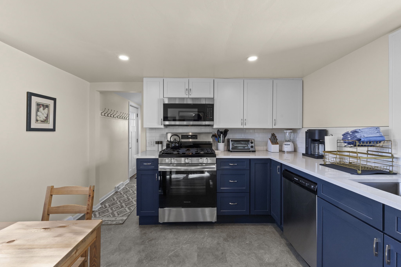 Freshly renovated kitchen with navy blue cabinets, quartz countertops, subway tile backsplash, and full suite of stainless steel appliances — everything you need to cook and entertain.