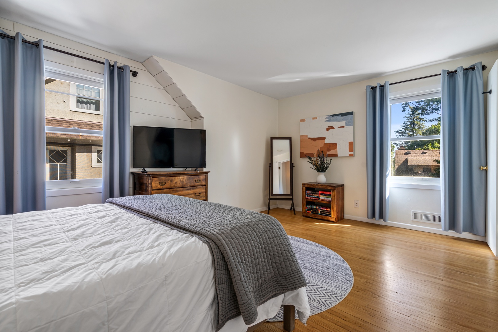 26 — Bright Summer Bedroom with Smart TV Vintage Dresser and Tree Lined Window Views