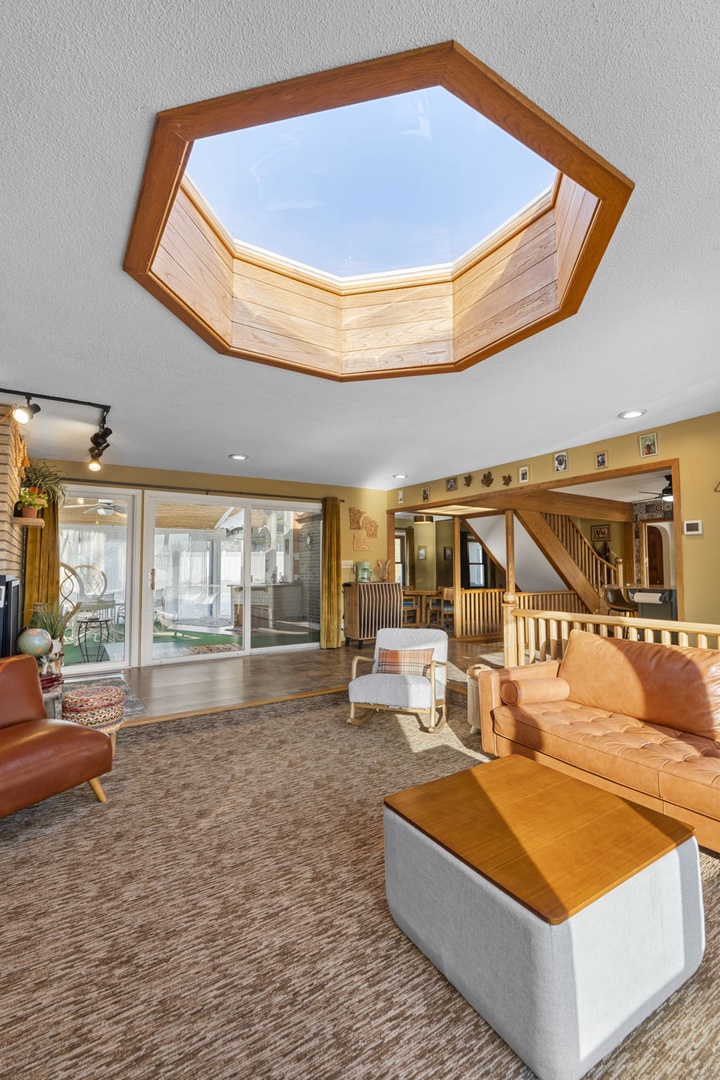 Your living room welcomes you with stunning skylights flooding warm natural light across rich leather seating and polished wood details.