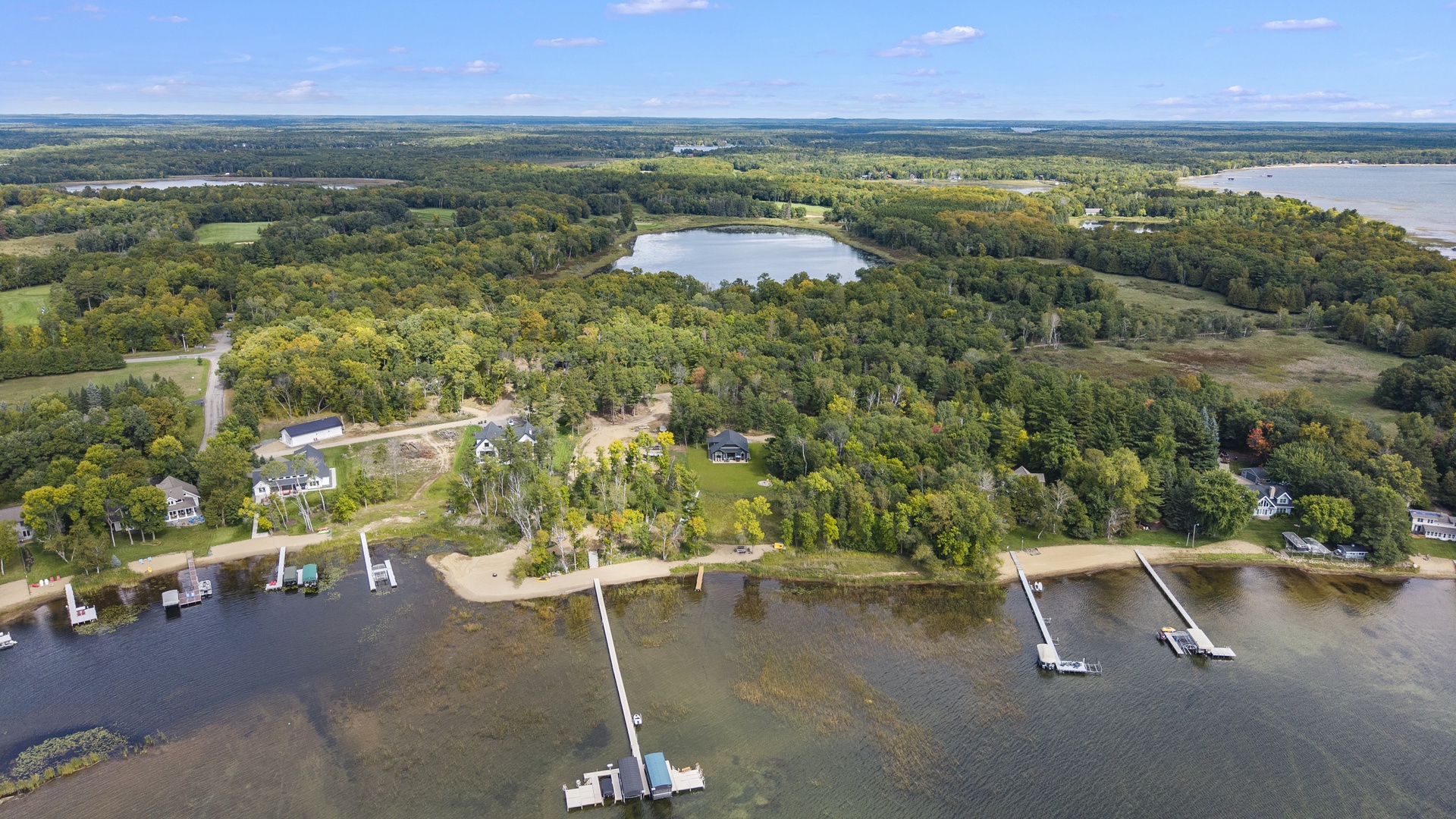 Aerial view showcasing the rental property's serene lakefront location, nestled among lush forests with private dock access and scenic waterways stretching across the peaceful landscape.