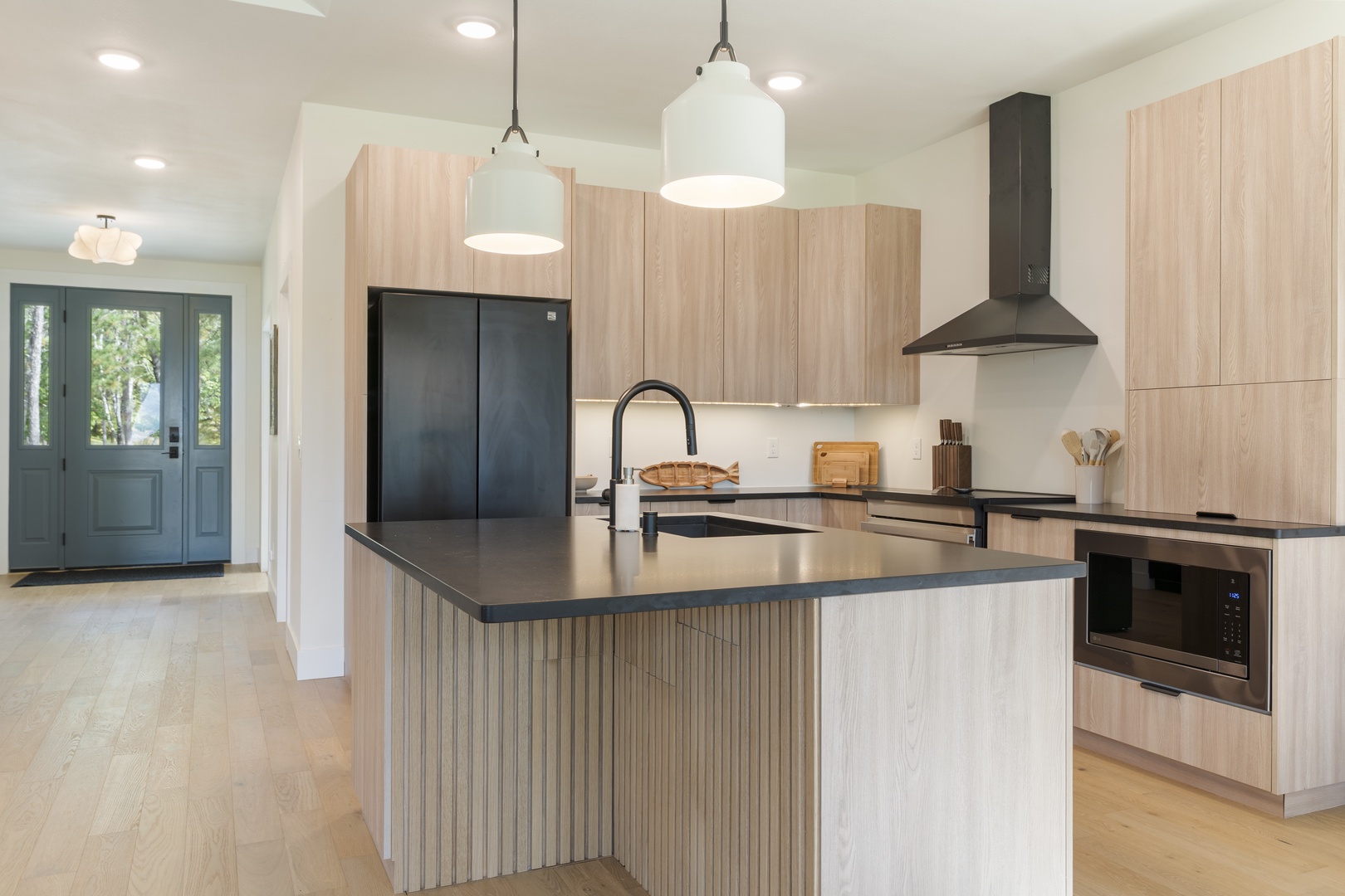 A bright, modern kitchen with sleek black countertops and warm wood cabinetry creates an inviting space where you can prepare memorable meals during your stay.