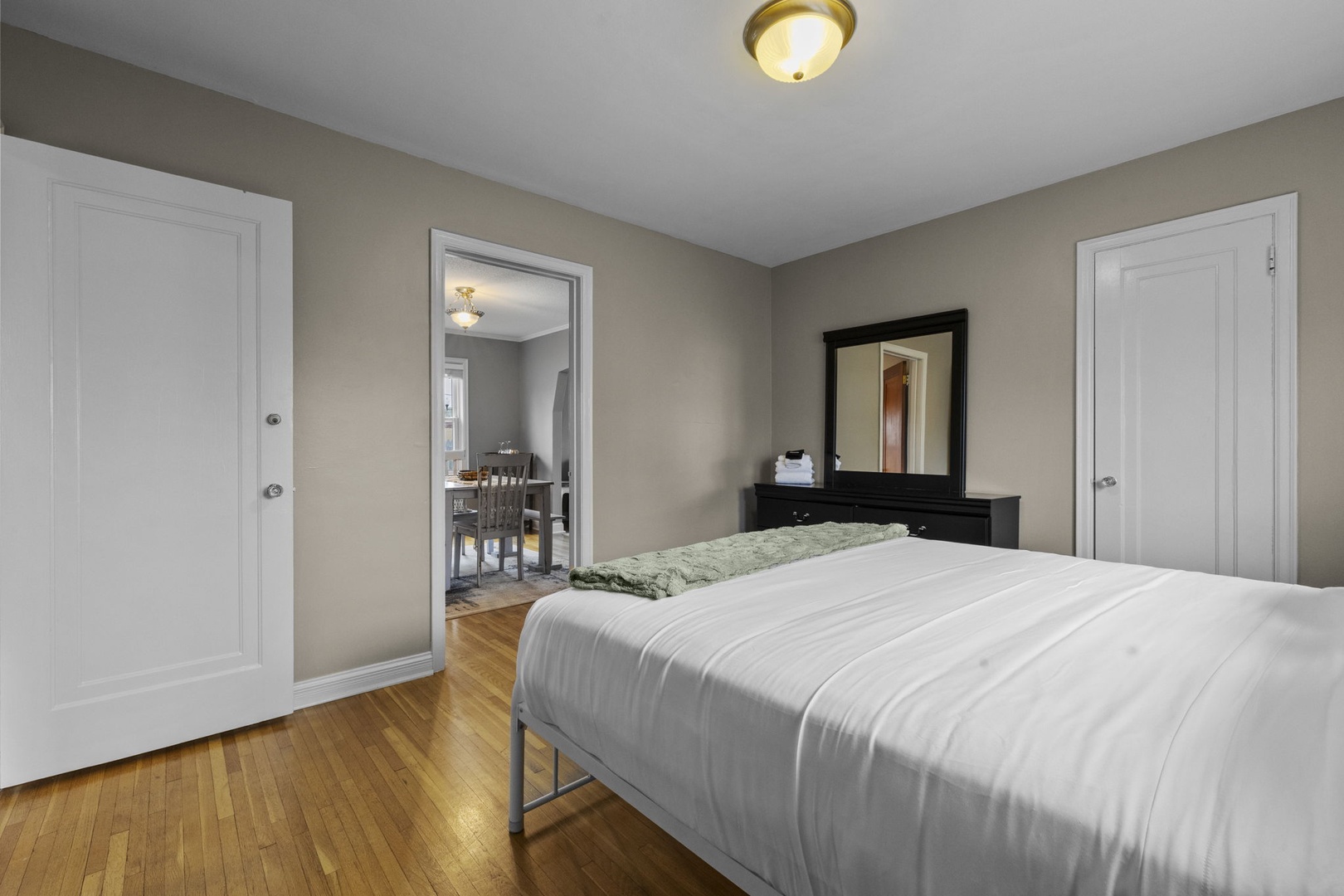 Sink into crisp linens and unwind in your serene bedroom, where soft neutral tones and warm hardwood floors create the perfect retreat after a day exploring the area.