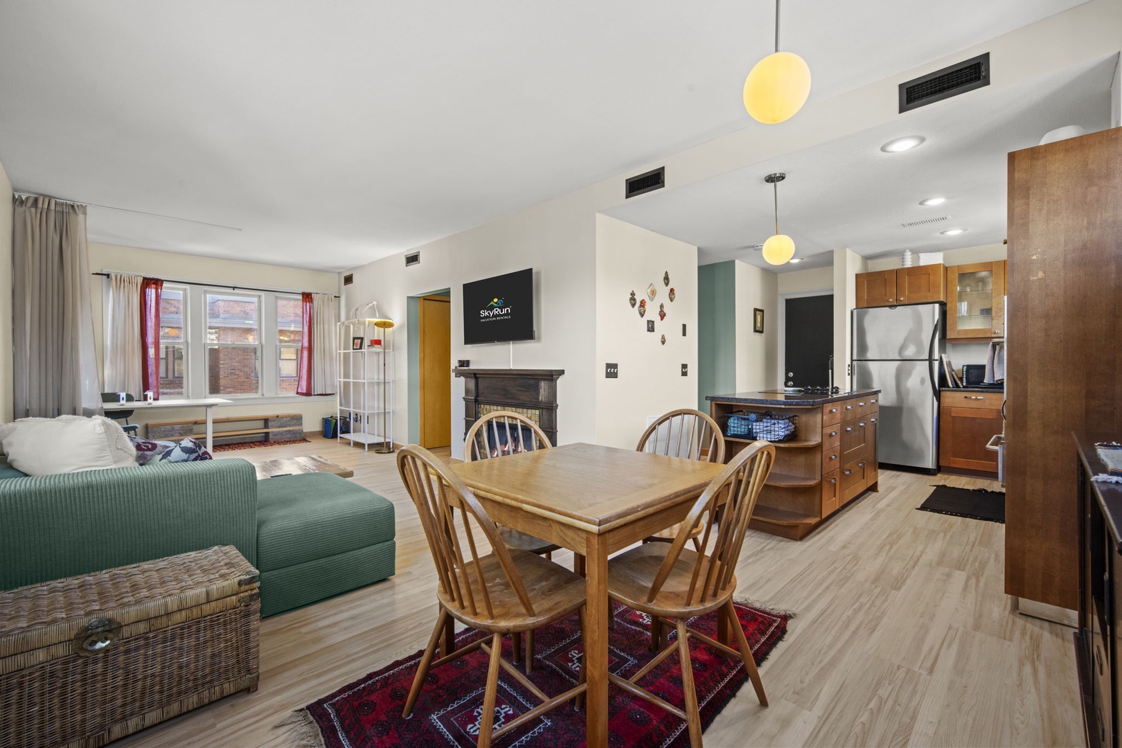 Step into your open-concept retreat, where light wood floors guide you through a thoughtfully designed living and dining space. Gather around the welcoming table or unwind on the cozy green couch while enjoying all the comforts of home.