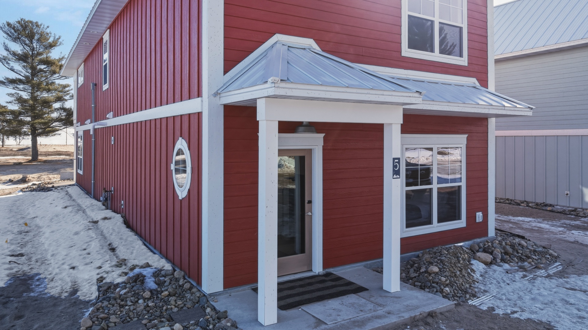 This distinctive red barn-style building features a charming covered entrance and modern touches, marking the arrival point to your vacation retreat.