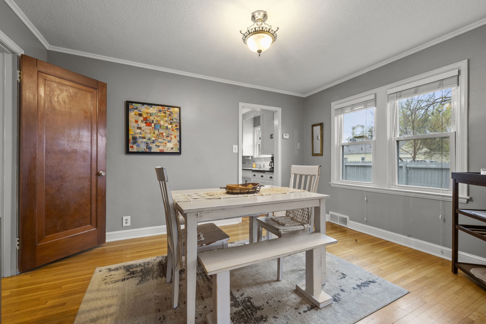 Picture yourself sharing meals at this inviting farmhouse-style table, surrounded by soft gray walls and warm natural light streaming through the windows. The space feels cozy yet open, perfect for your morning coffee or relaxed evening dinners.