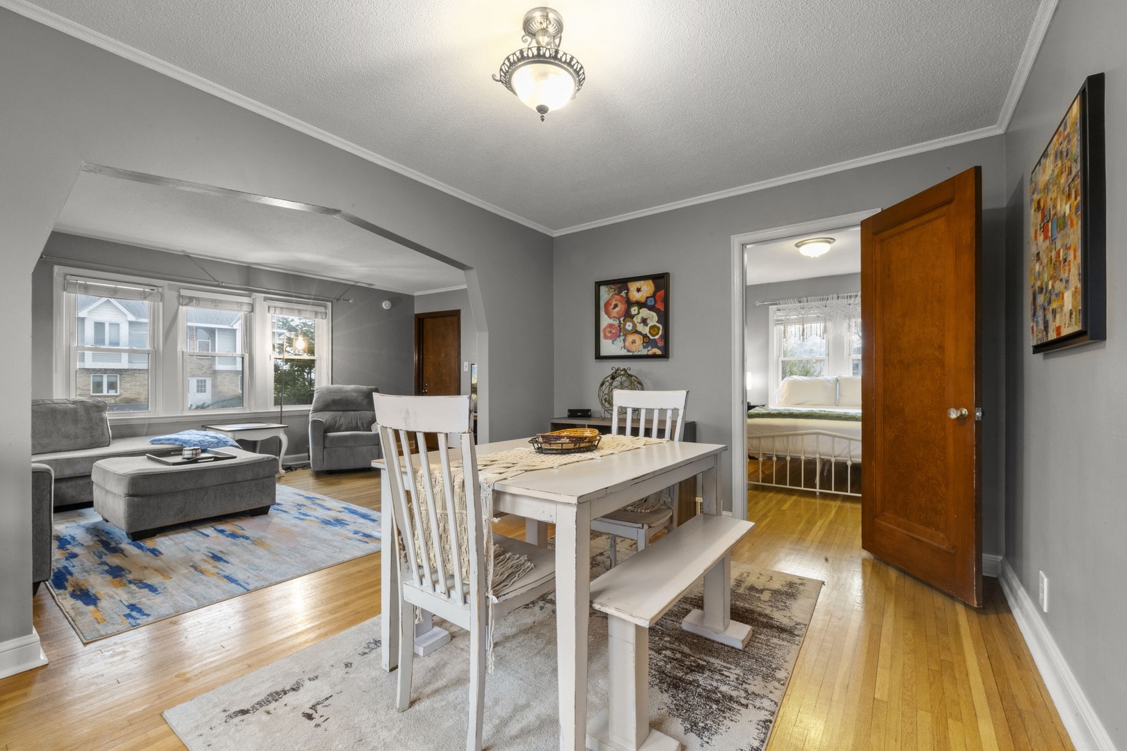 Step into your inviting open-concept living and dining area, where soft gray walls and gleaming hardwood floors create a peaceful retreat. Settle into the cozy living room, gather around the charming dining table, or retreat to your sunny bedroom.