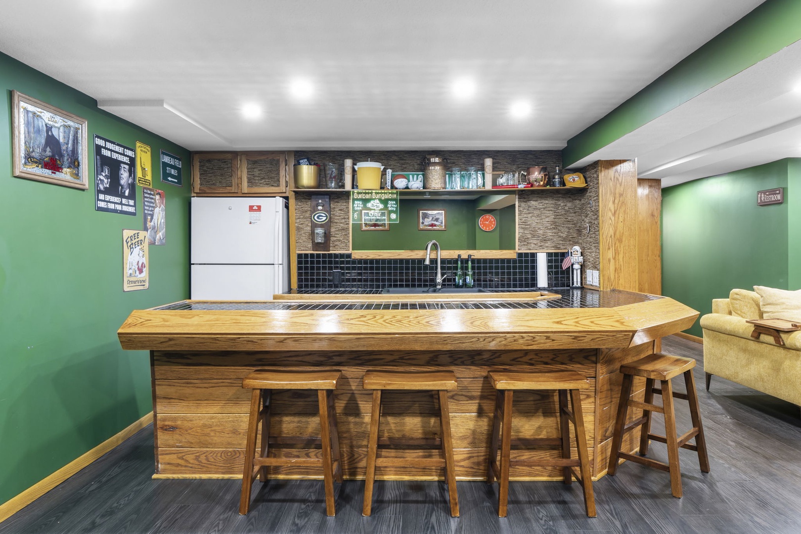 Your own sports-themed bar awaits with custom wood counter, four stools, and full kitchen behind—perfect for game day gatherings.
