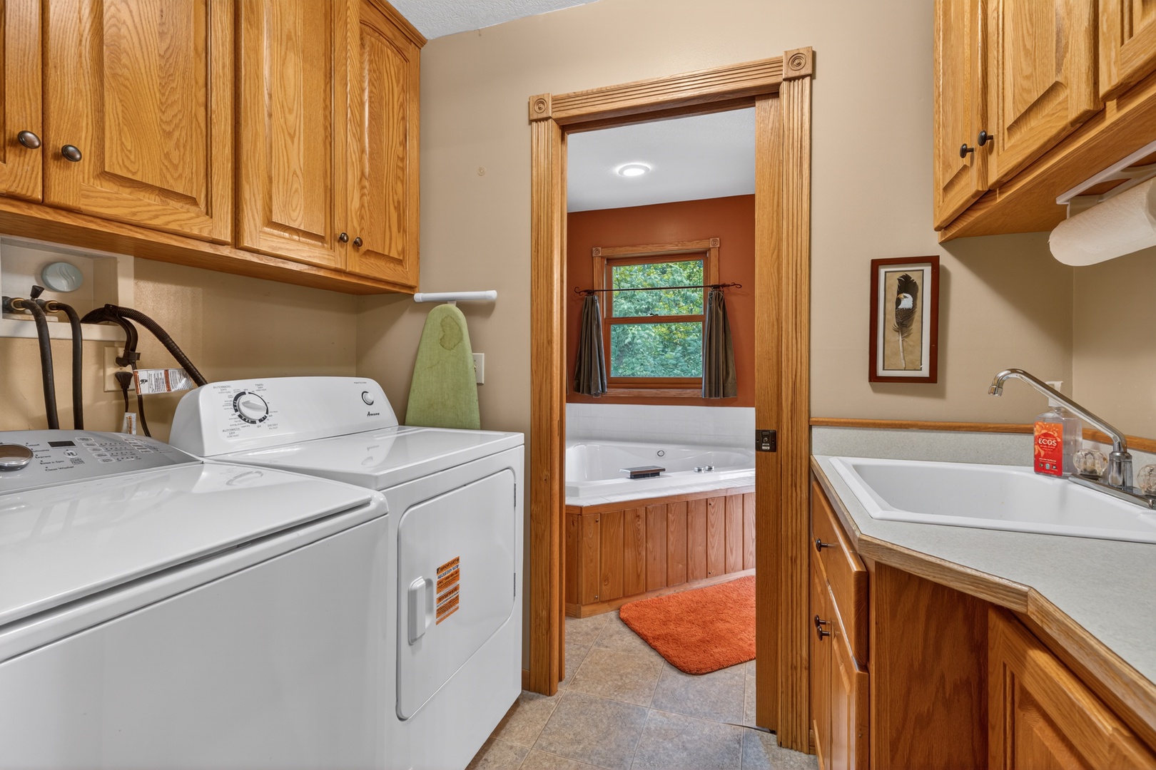 Step into a well-equipped laundry space with a side-by-side washer and dryer, plus a convenient sink for all your needs. Through the doorway, you'll find a peaceful hot tub retreat waiting to melt your stress away.