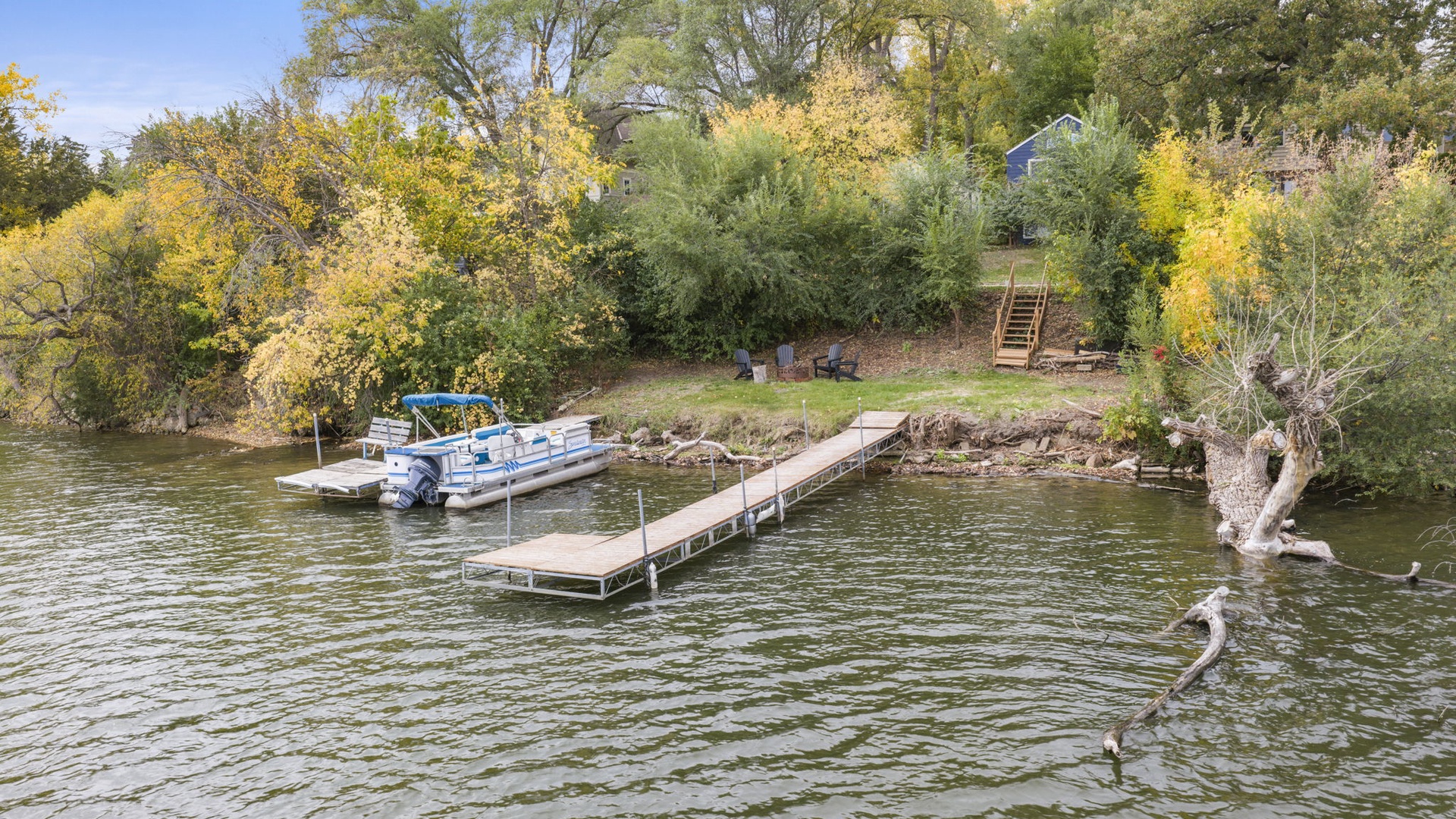 A scenic lakefront location, with lush autumn-colored trees and a gentle hillside path leading to the grounds above.