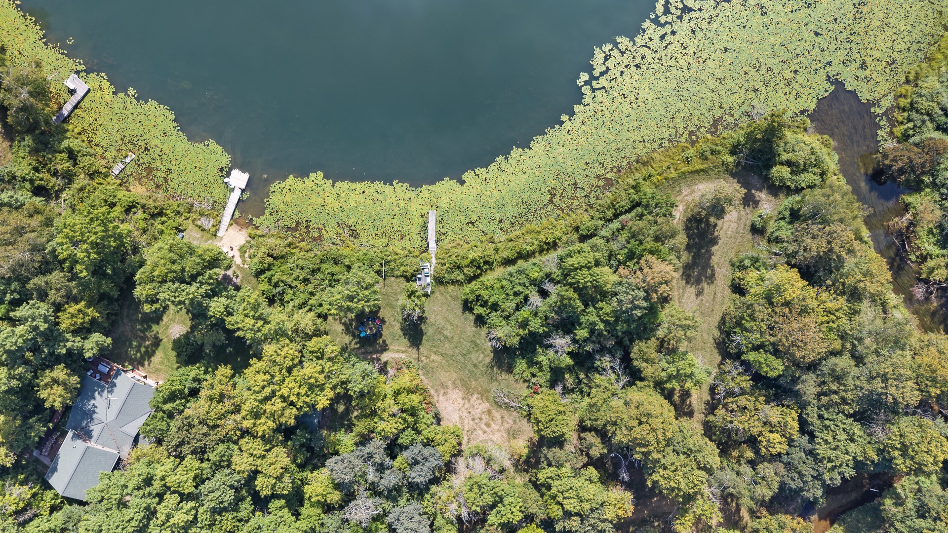Aerial view showcasing a secluded waterfront property surrounded by lush greenery and natural landscape, with private dock access along the tranquil shoreline.