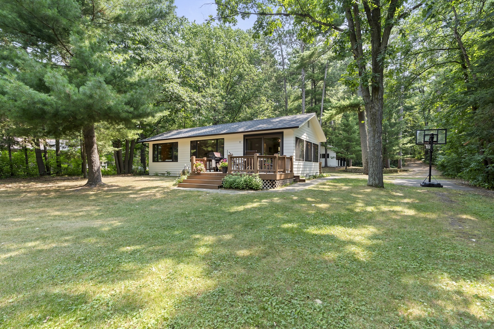 Nestled among towering pines on a spacious, sun-dappled lawn, this charming retreat offers a welcoming front porch and peaceful wooded surroundings perfect for your getaway.