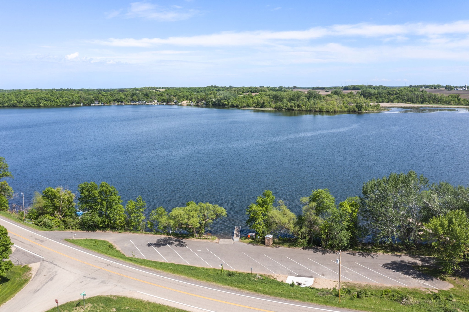 Scenic lake setting surrounded by lush greenery and wooded shoreline. The property's location offers easy access to tranquil waterfront views and nearby outdoor recreation.