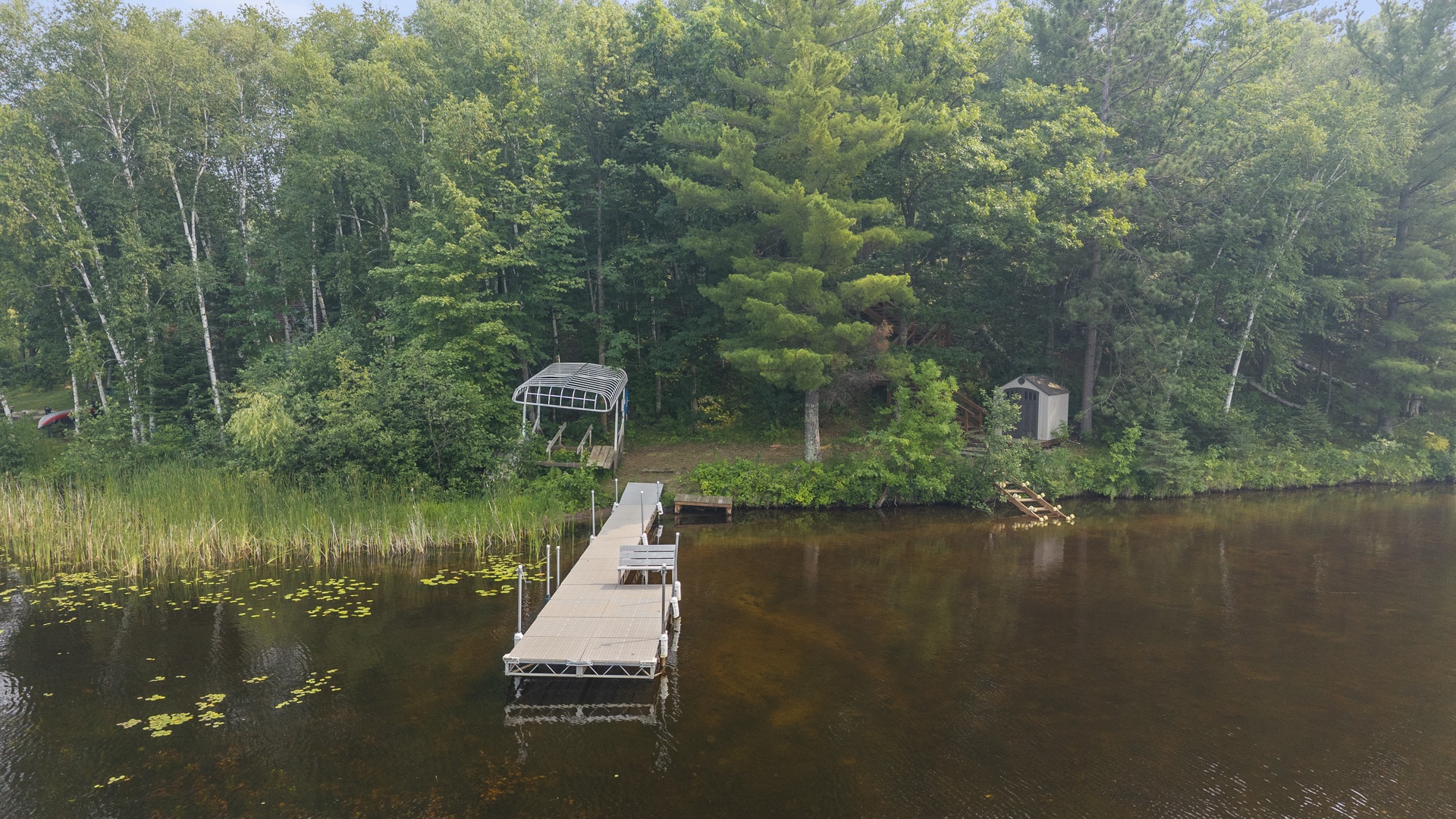 A peaceful lakeside dock offers direct water access, perfect for kayaking and fishing, with a boat lift ready for summer adventures. The wooded shoreline provides privacy and natural beauty.