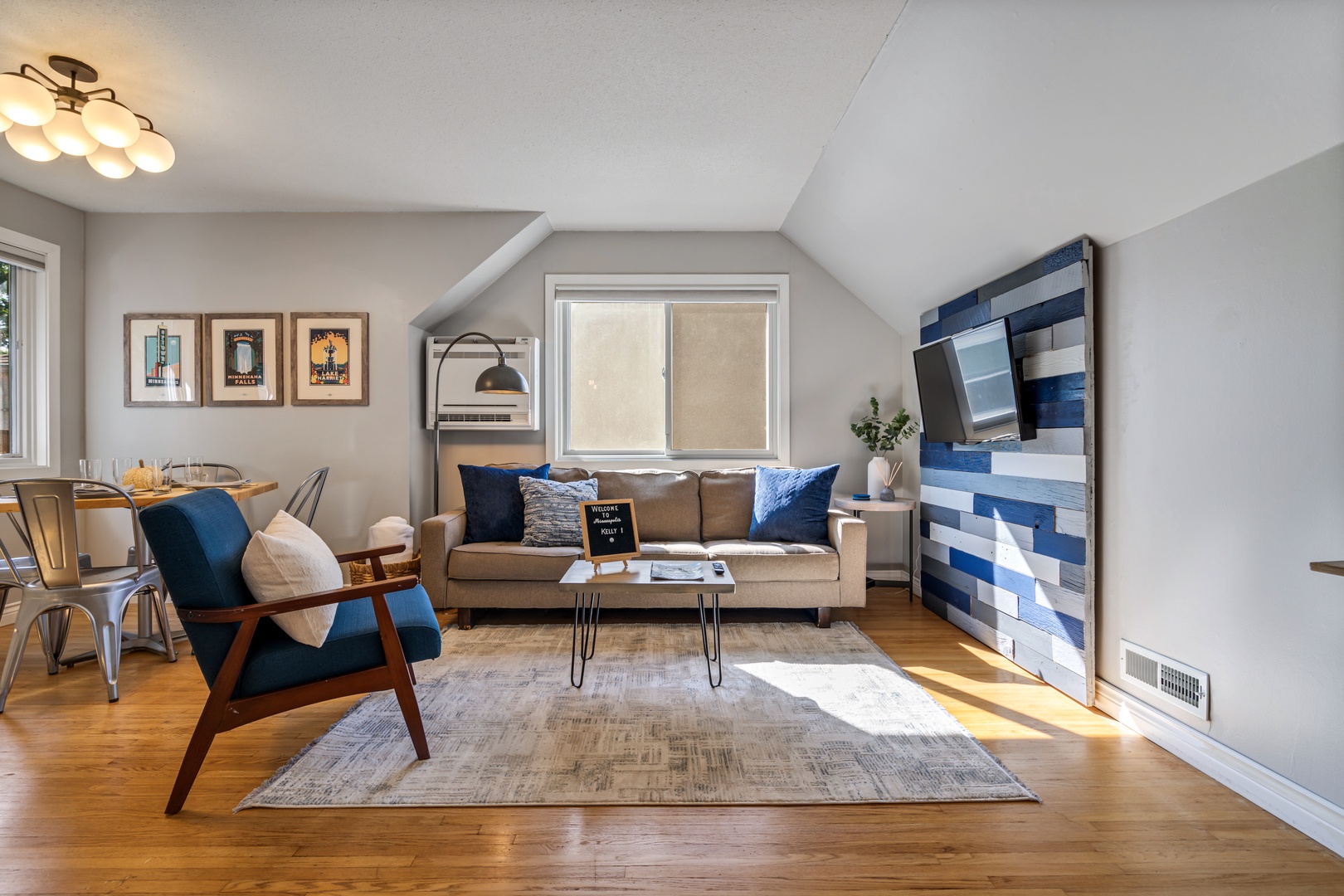 Relax in your stylish living room with cozy seating, warm wood floors, and cheerful natural light streaming through large windows.