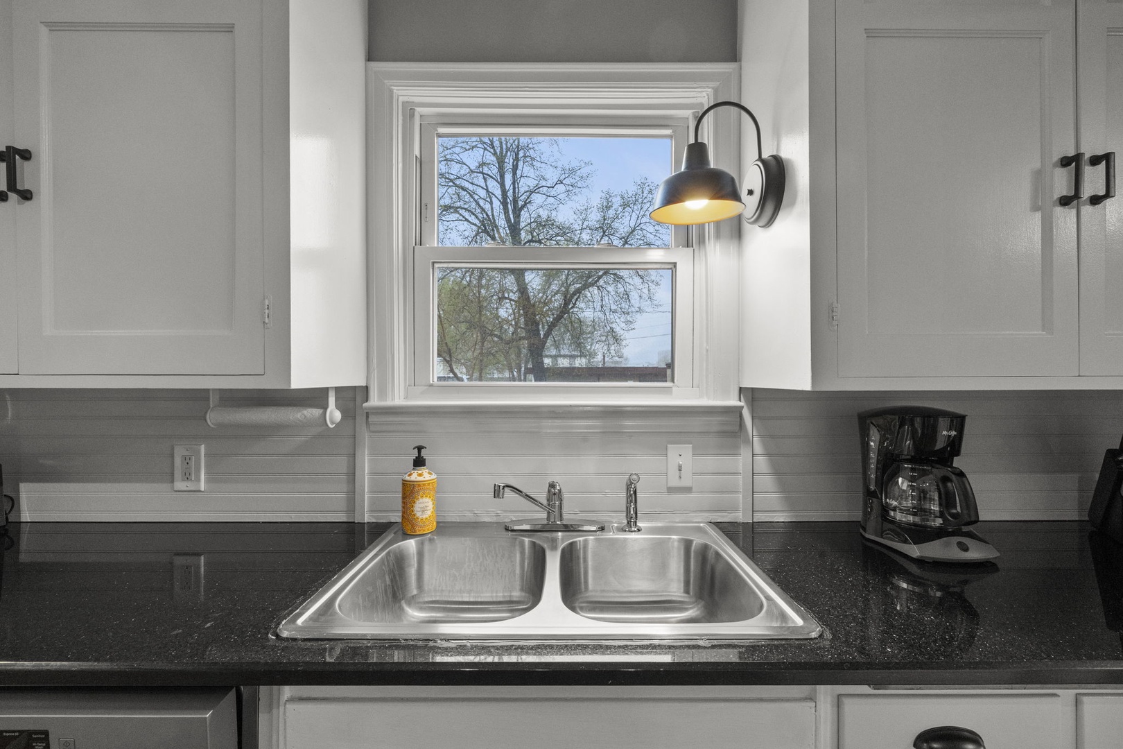 A bright, modern kitchen awaits you with sleek countertops, a double-basin sink, and a charming view of the outdoors. Perfect for brewing your morning coffee and planning your day.
