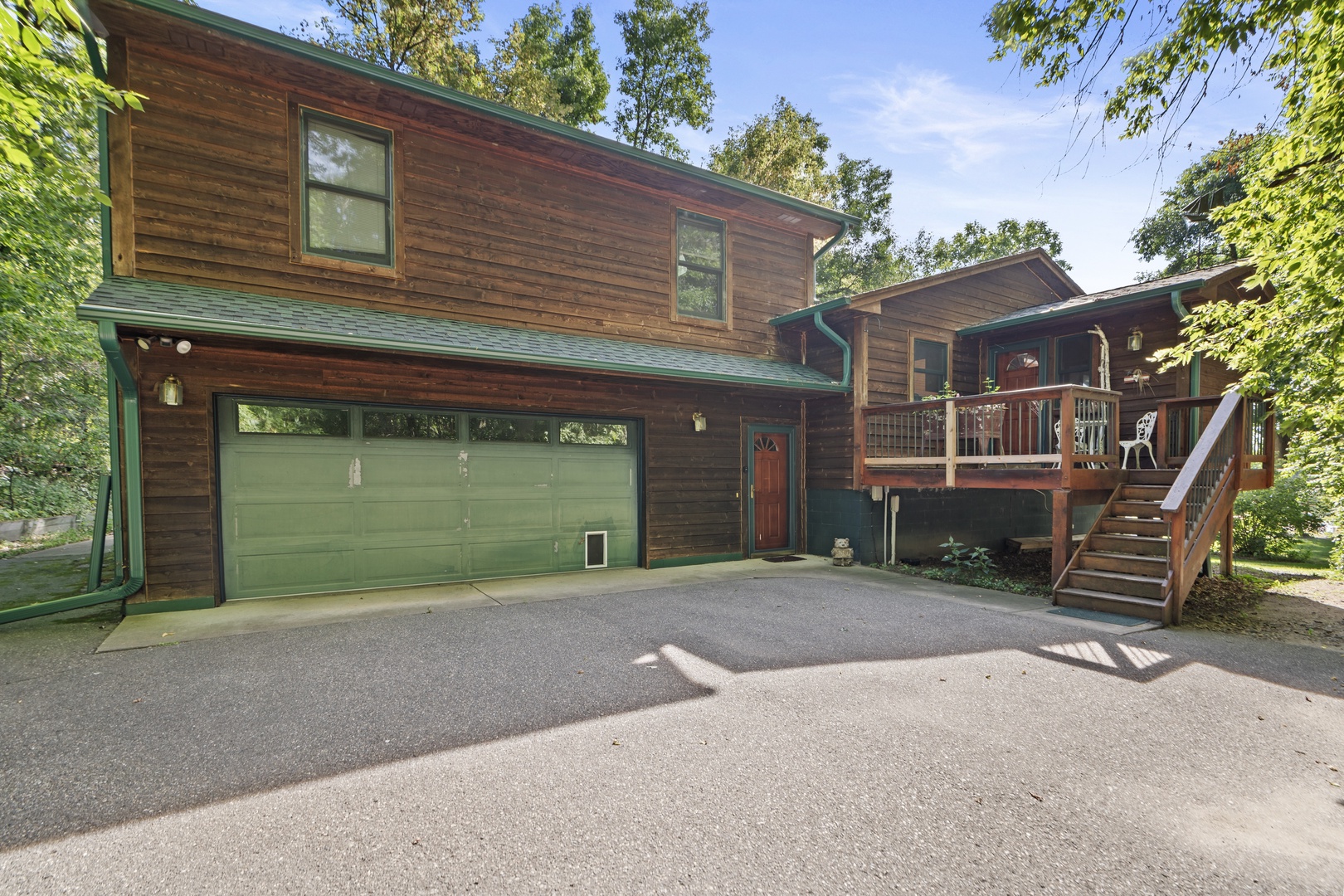 A charming cedar-sided property with two-car garage and private deck, nestled among mature trees in a peaceful residential setting.
